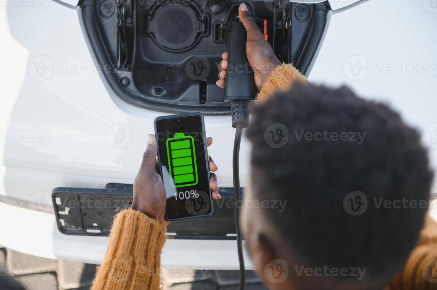 Smartphone app shows charging status of the electric car battery. Electro transport concept photo
