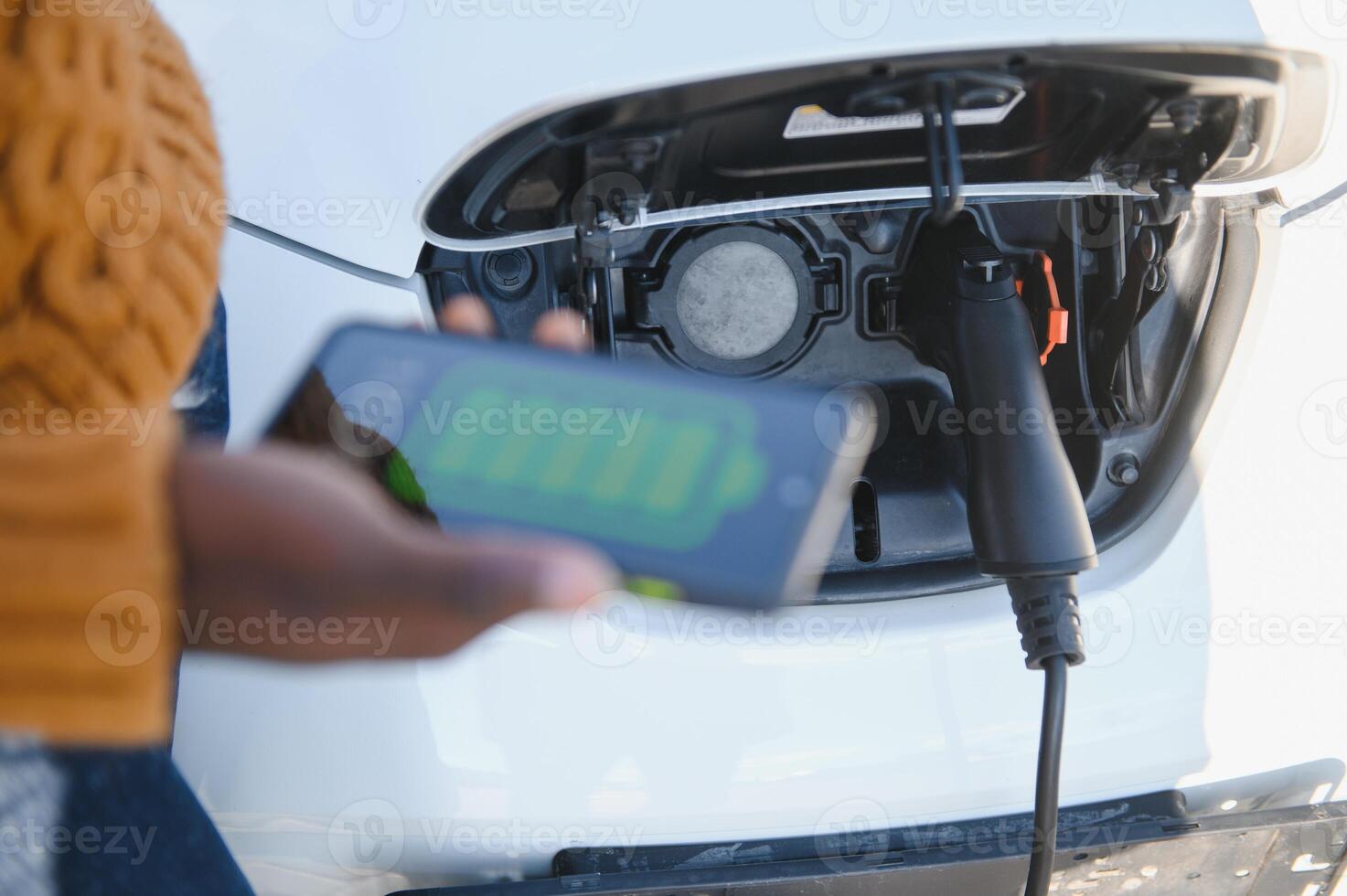 Smartphone app shows charging status of the electric car battery. Electro transport concept photo