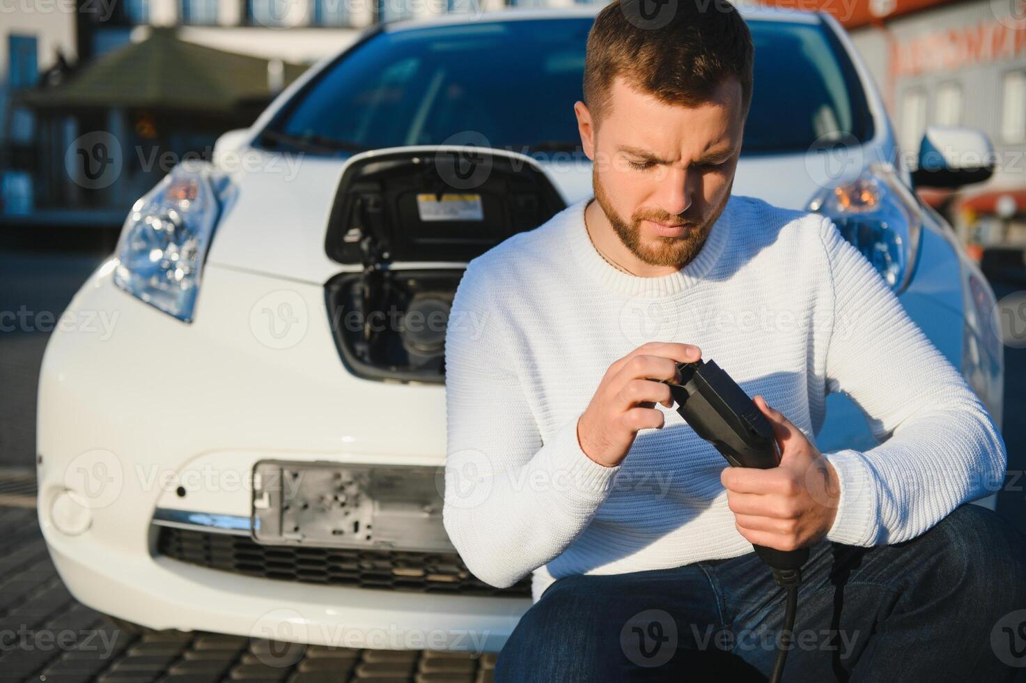 Smiling man unplugging the charger from the car photo