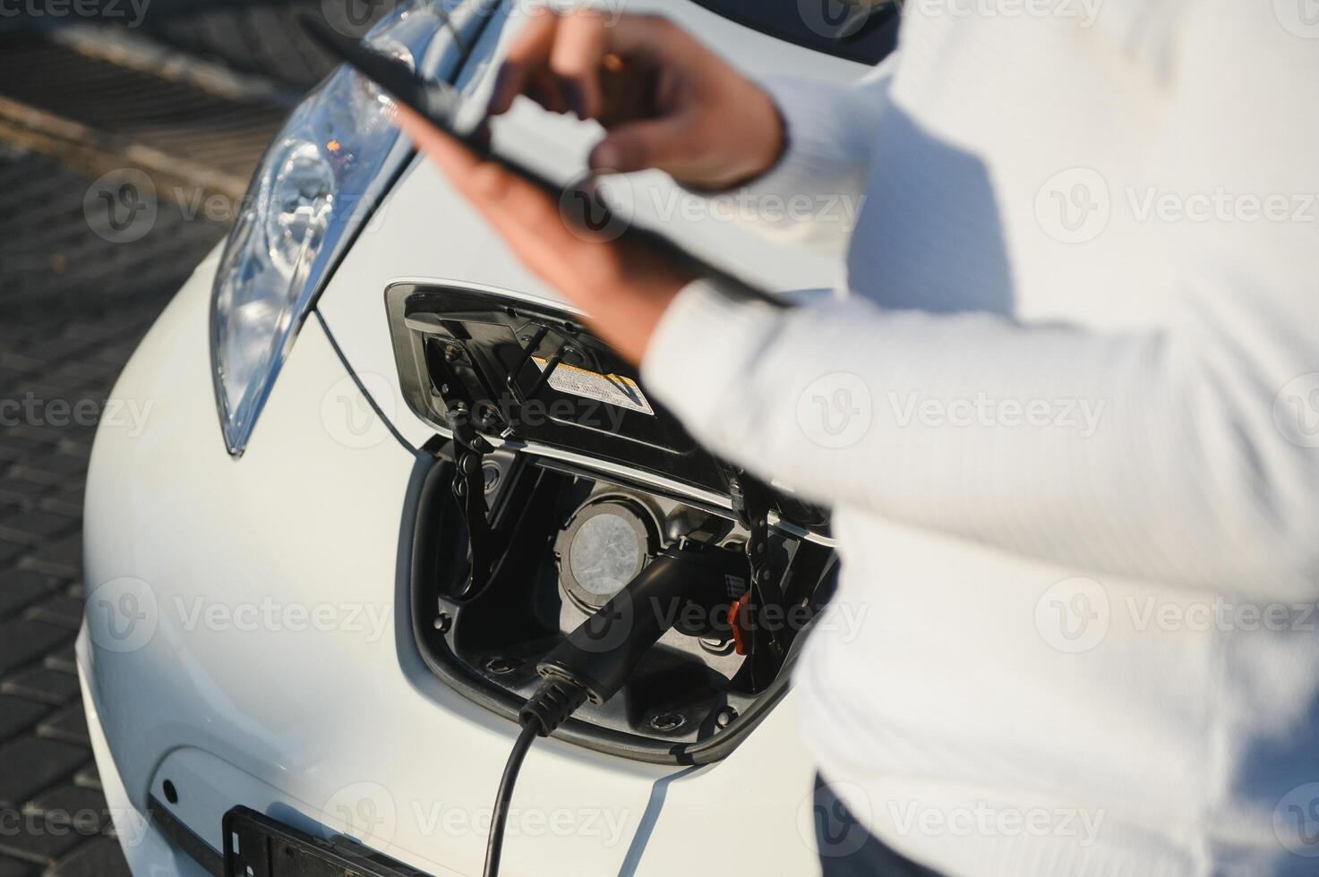 Man charges an electric car at the charging station photo