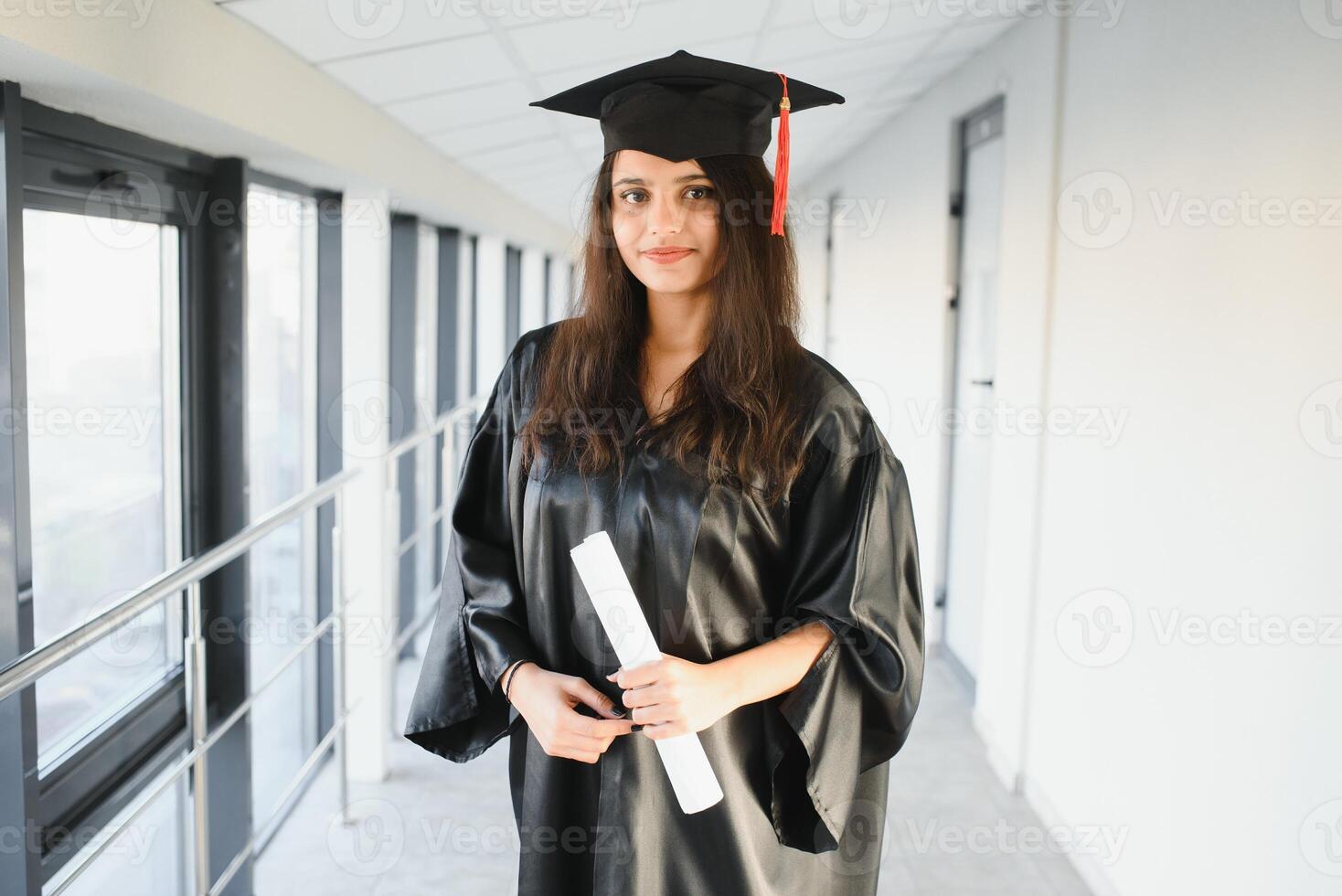 Happy Indian university student in graduation gown and cap holding diploma certificate. photo