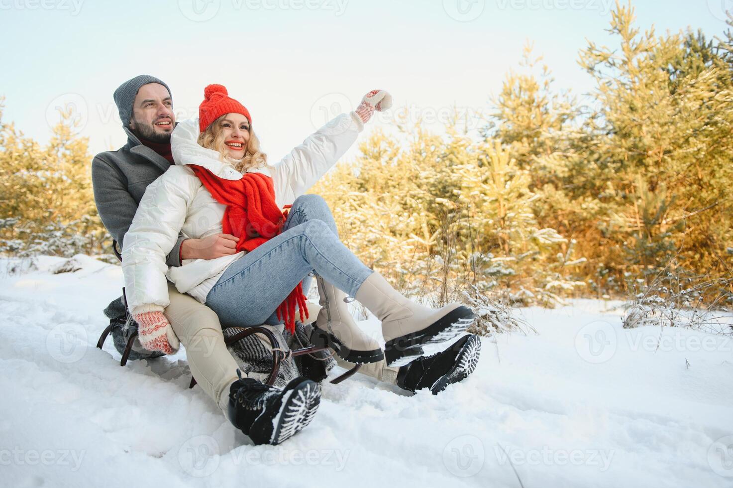 A side view of a happy couple having fun while sliding downhill together over snowy slope using a sled photo