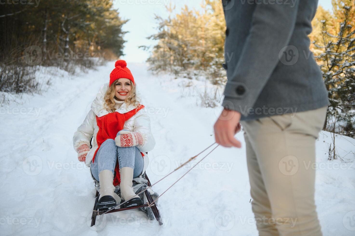 A side view of a happy couple having fun while sliding downhill together over snowy slope using a sled photo