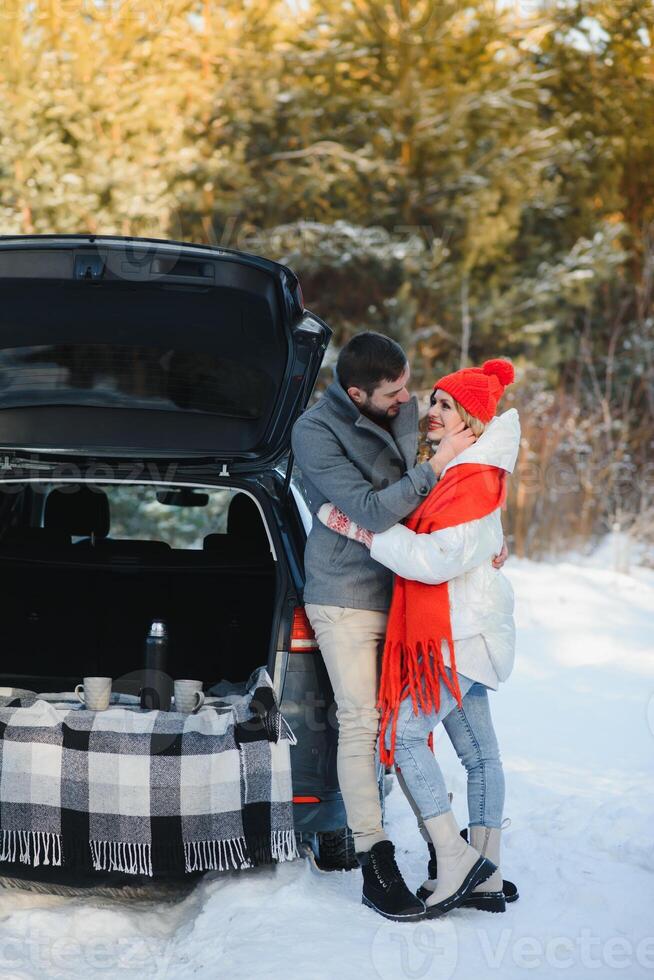 Winter picnic in the forest. Love story in snow. couple in winter play in snow and hugging near the pine. Two lovers on winter walk. Valentine's Day for couple in rustic style. Winter lovestory photo