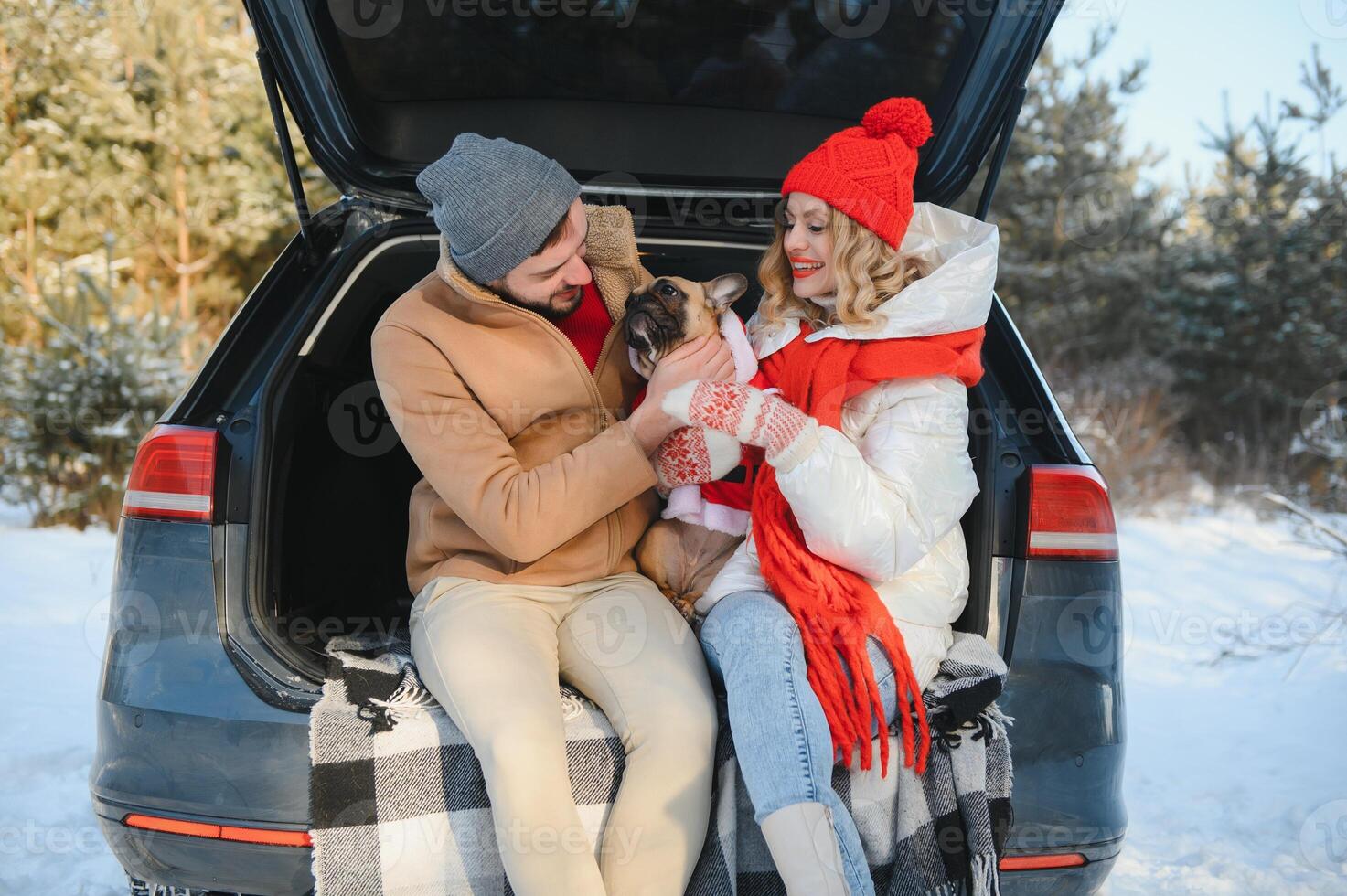 couple guy and girl sitting in car playing with dog in winter forest photo