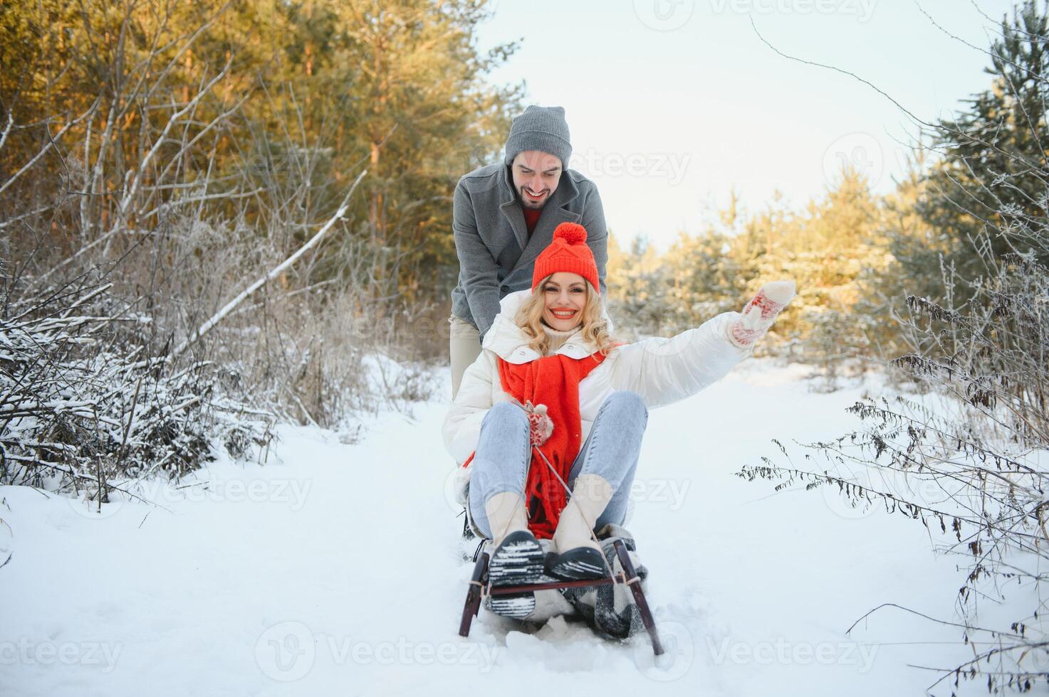 Beautiful young couple in love having fun on a winter vacation in mountains, boyfriend pushing girlfriend on a sled, enjoying snowy, foggy winter day outdoor photo