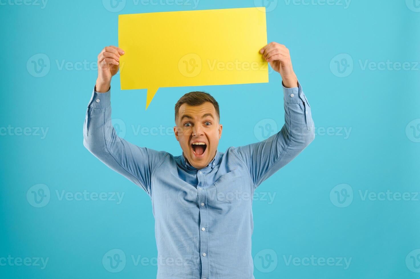 guy holding speech bubble on blue studio background, mockup for design photo