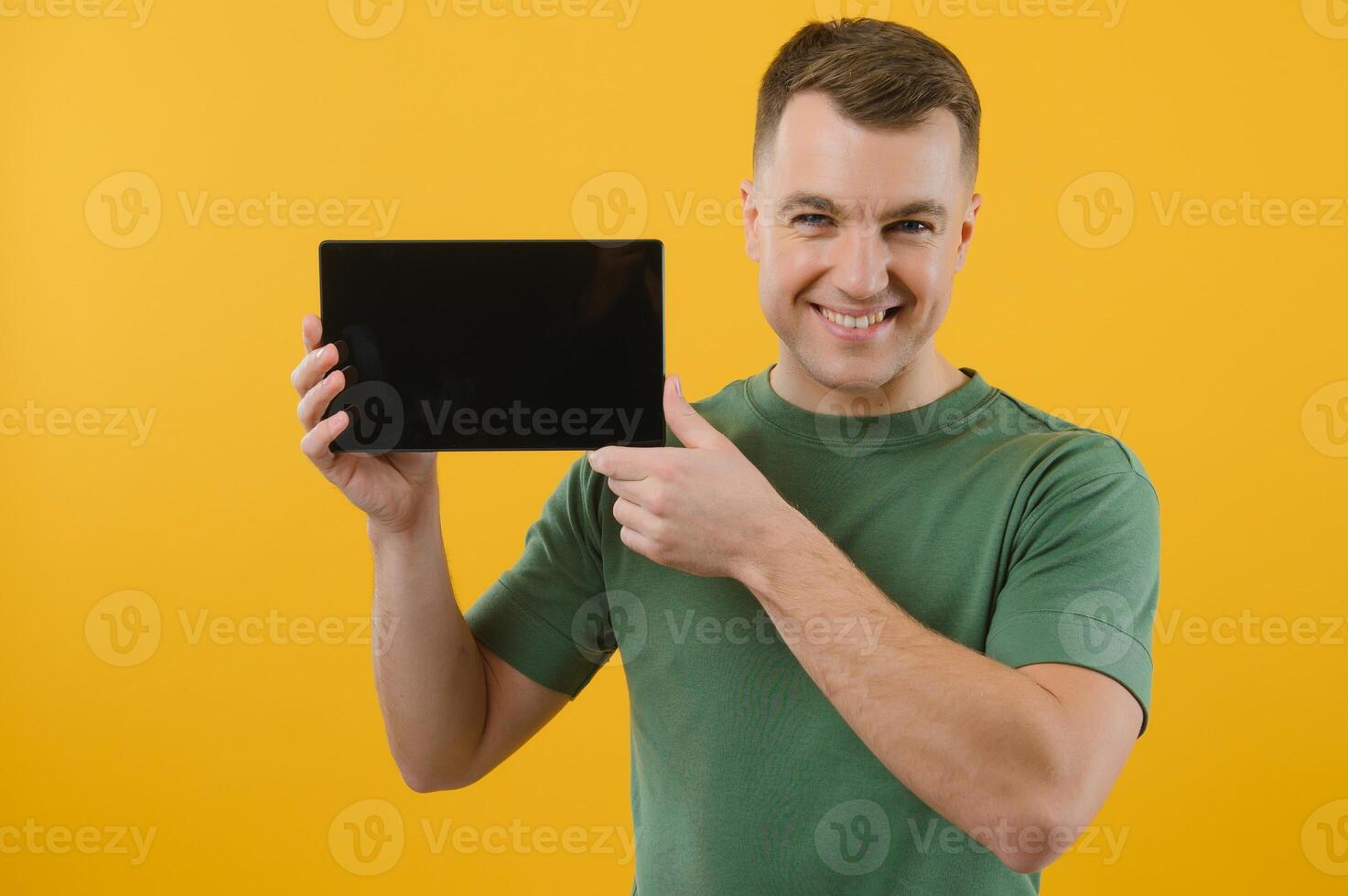 Amazed happy man using digital tablet looking shocked about social media news, astonished man shopper consumer surprised excited by online win isolated over yellow background. photo