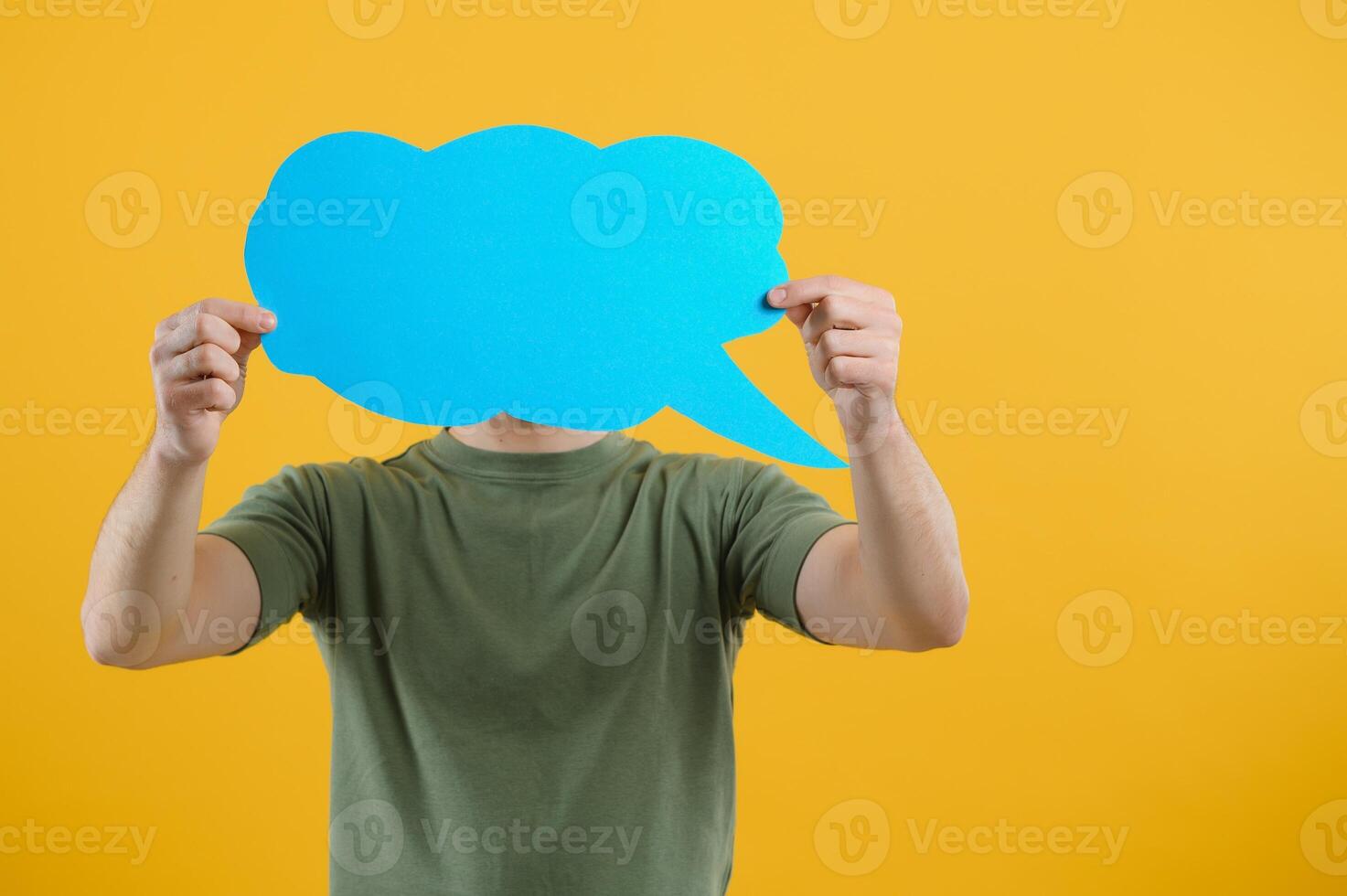 Handsome man holding blank speech bubble sign isolated on yellow studio background photo