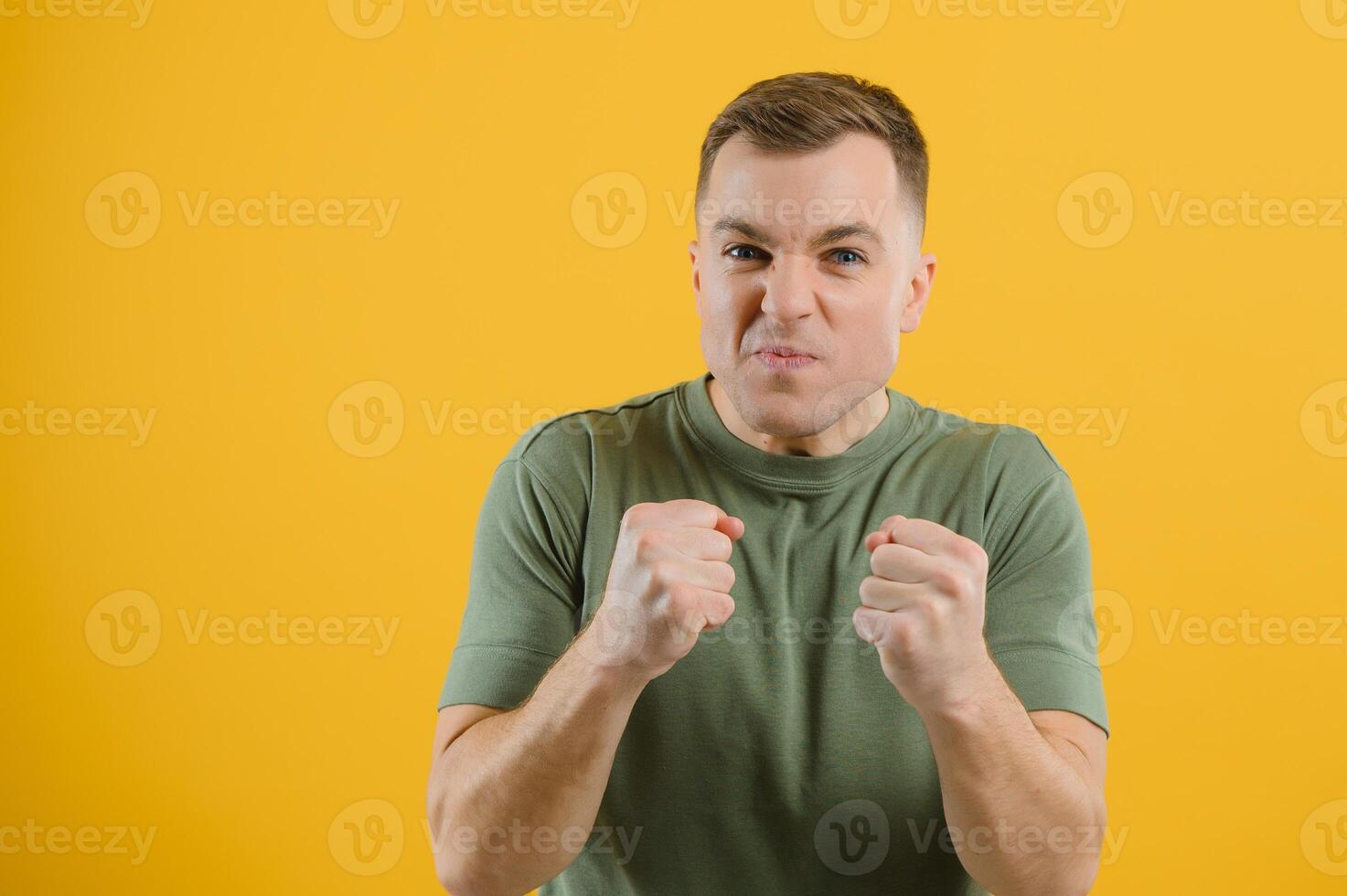 Excited young man guy posing isolated on yellow background studio portrait. People lifestyle concept. Mock up copy space. Rising hands, clenching fists like winner photo