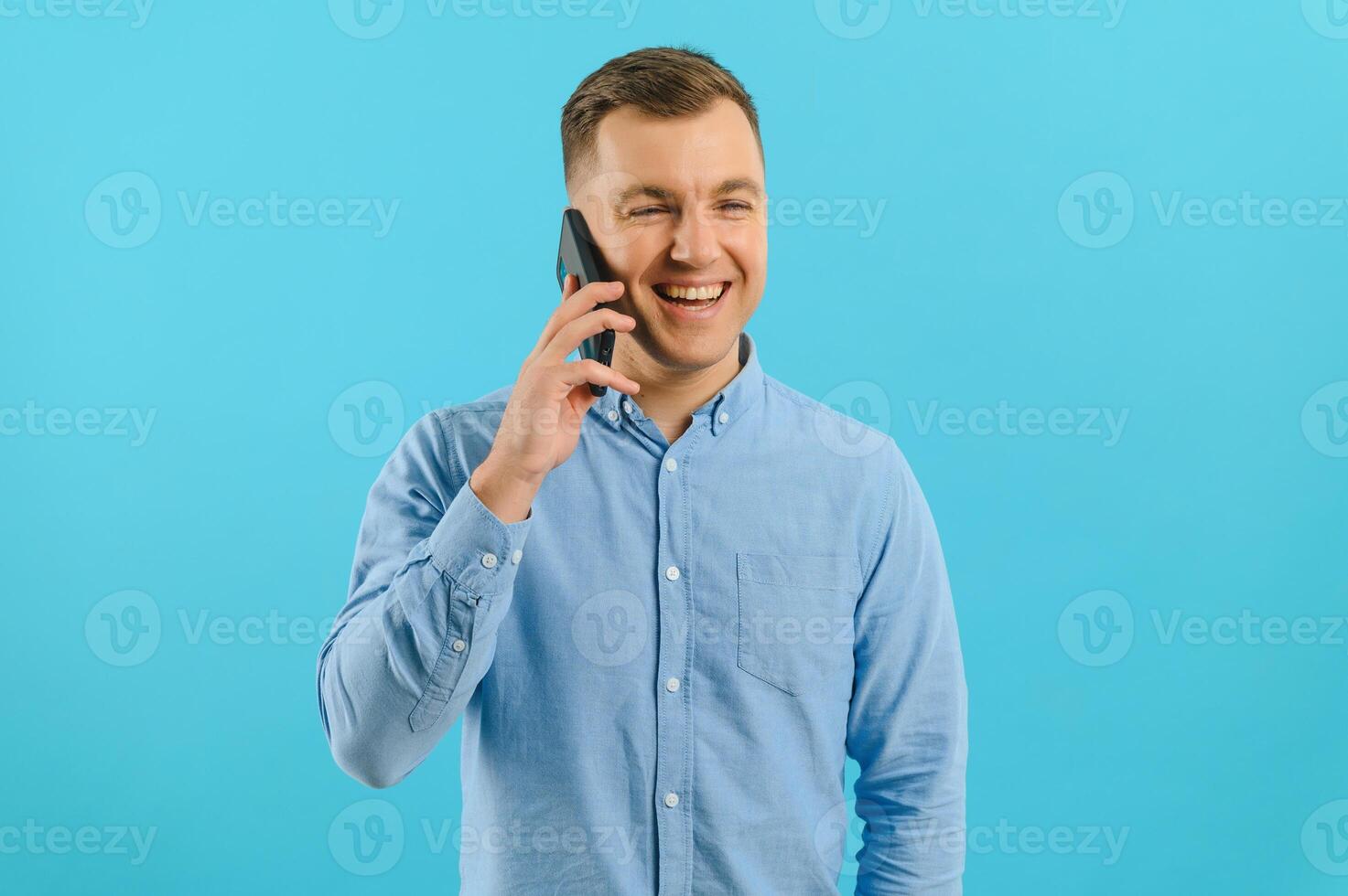 Young man in bright colorful wear talking on mobile cell phone on blue background. Trendy guy have conversation. Smartphone, technology concept. photo