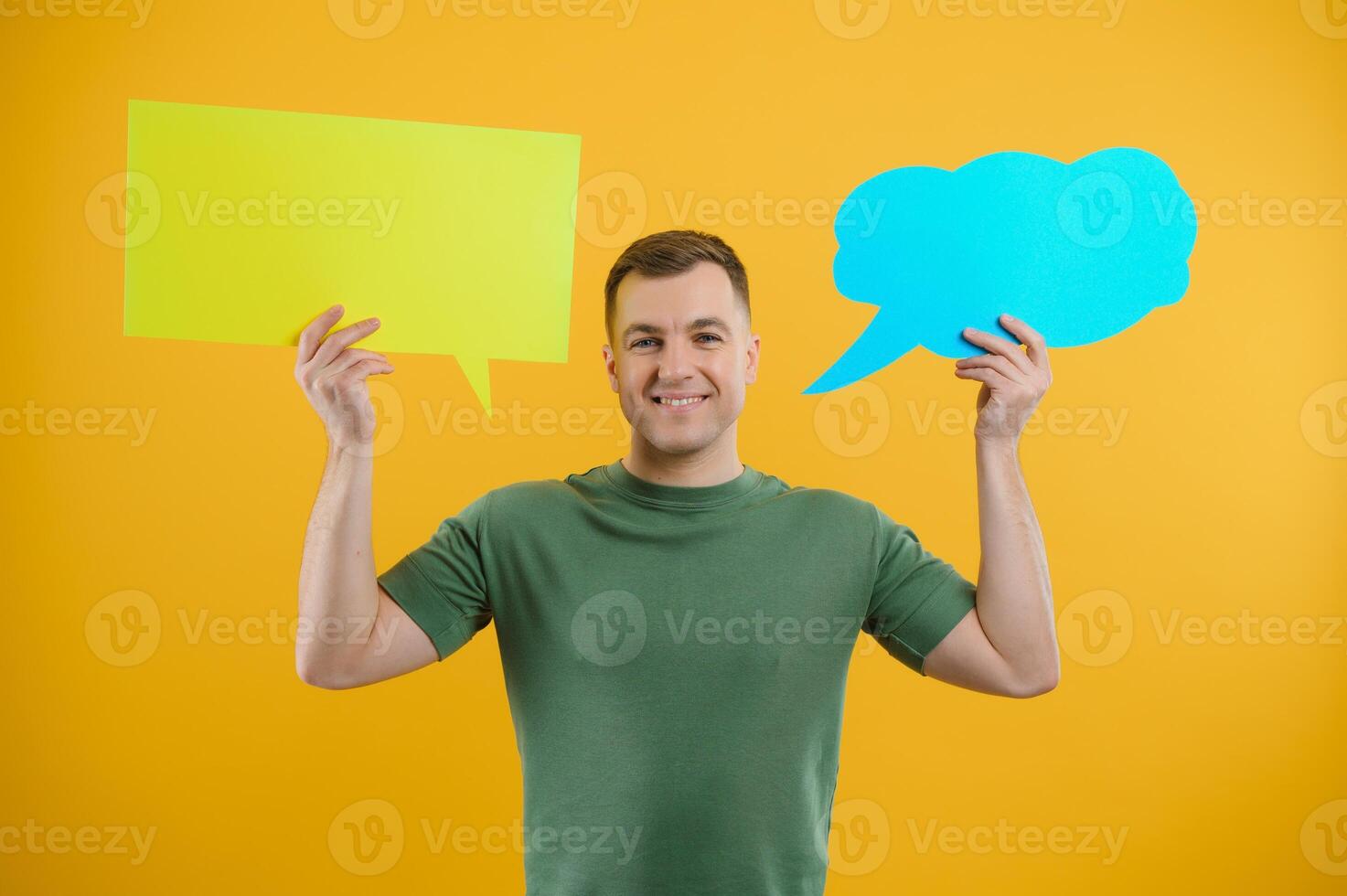 Cheerful young male pointing up and holding empty speech bubble with blank space for quote against vivid yellow background photo