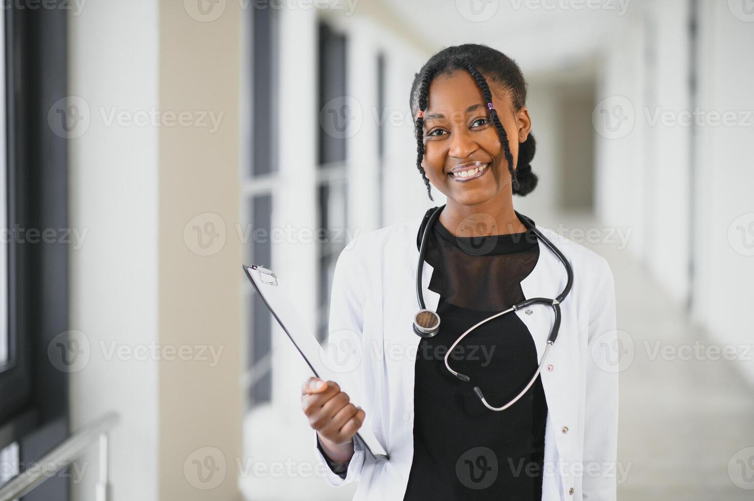 Closeup portrait of friendly, smiling confident female healthcare professional with lab coat, stethoscope. Isolated hospital clinic background. Time for an office visit photo