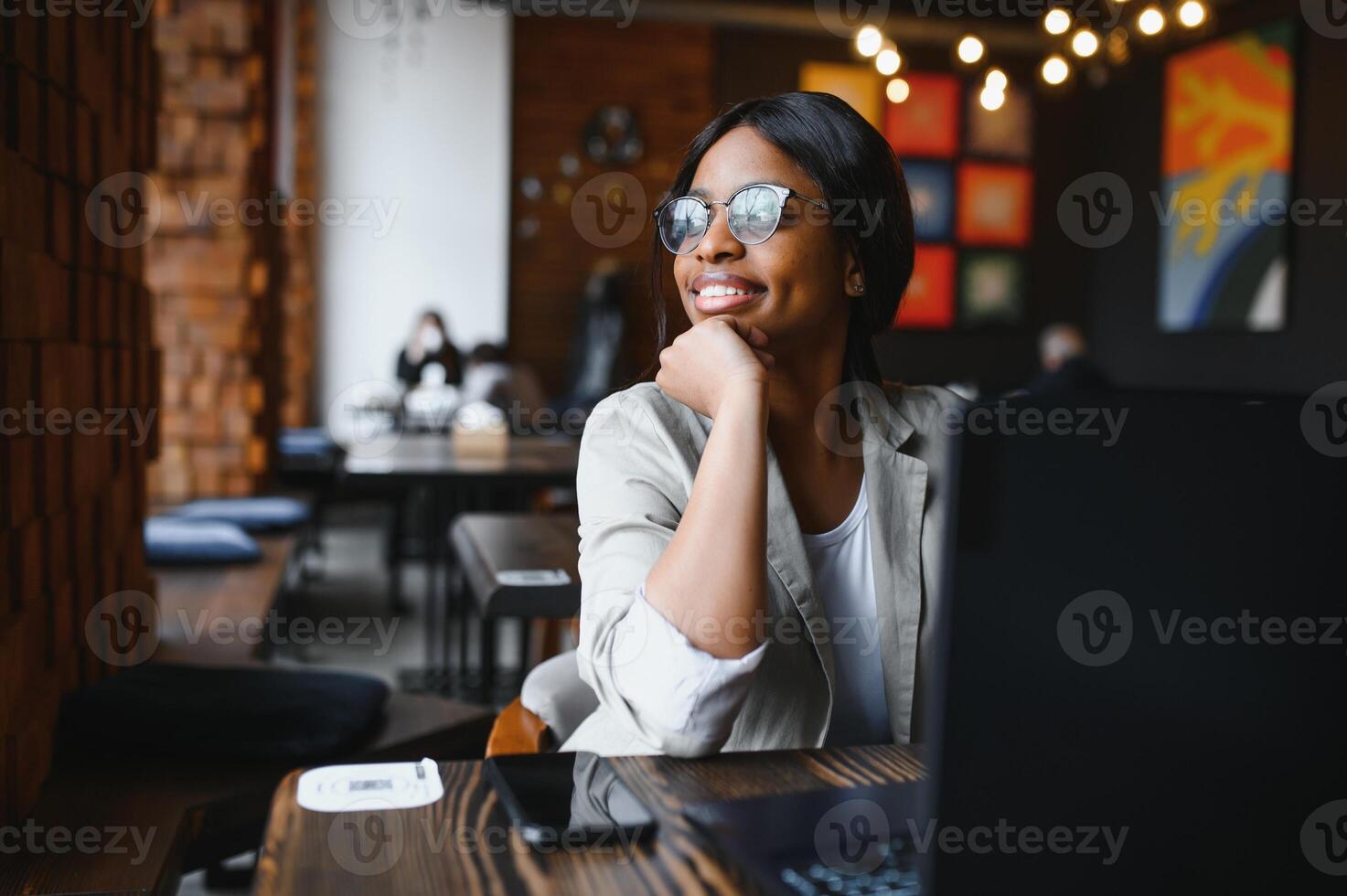 Happy african american woman worker using laptop work study at computer in loft office or cafe, smiling mixed race female student freelancer using pc app dating communicating online watching webinar photo