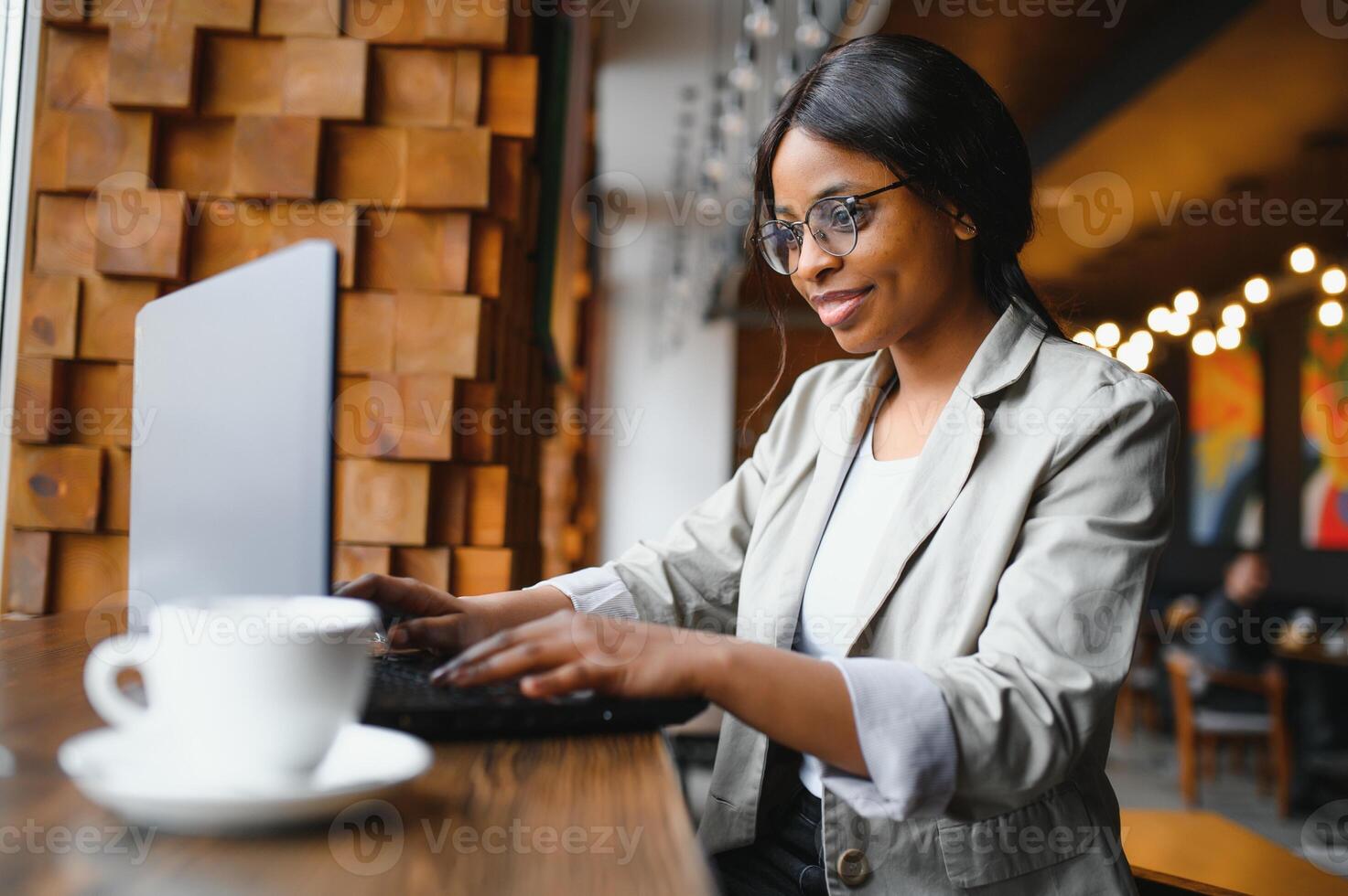 Happy african american woman worker using laptop work study at computer in loft office or cafe, smiling mixed race female student freelancer using pc app dating communicating online watching webinar photo