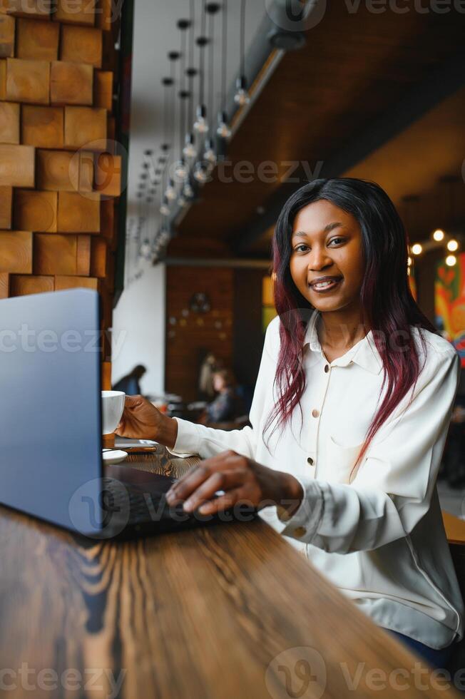 Lucky day. Emotional black woman looking at laptop, clenching fists and screaming, working at cafe, copy space photo