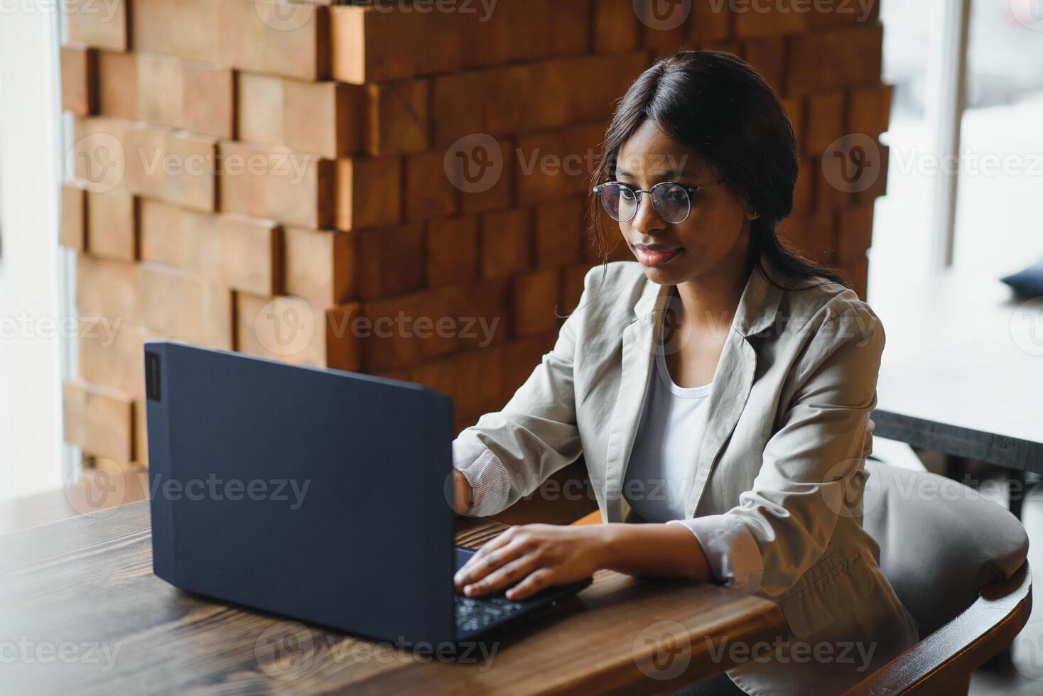 Happy african american woman worker using laptop work study at computer in loft office or cafe, smiling mixed race female student freelancer using pc app dating communicating online watching webinar photo