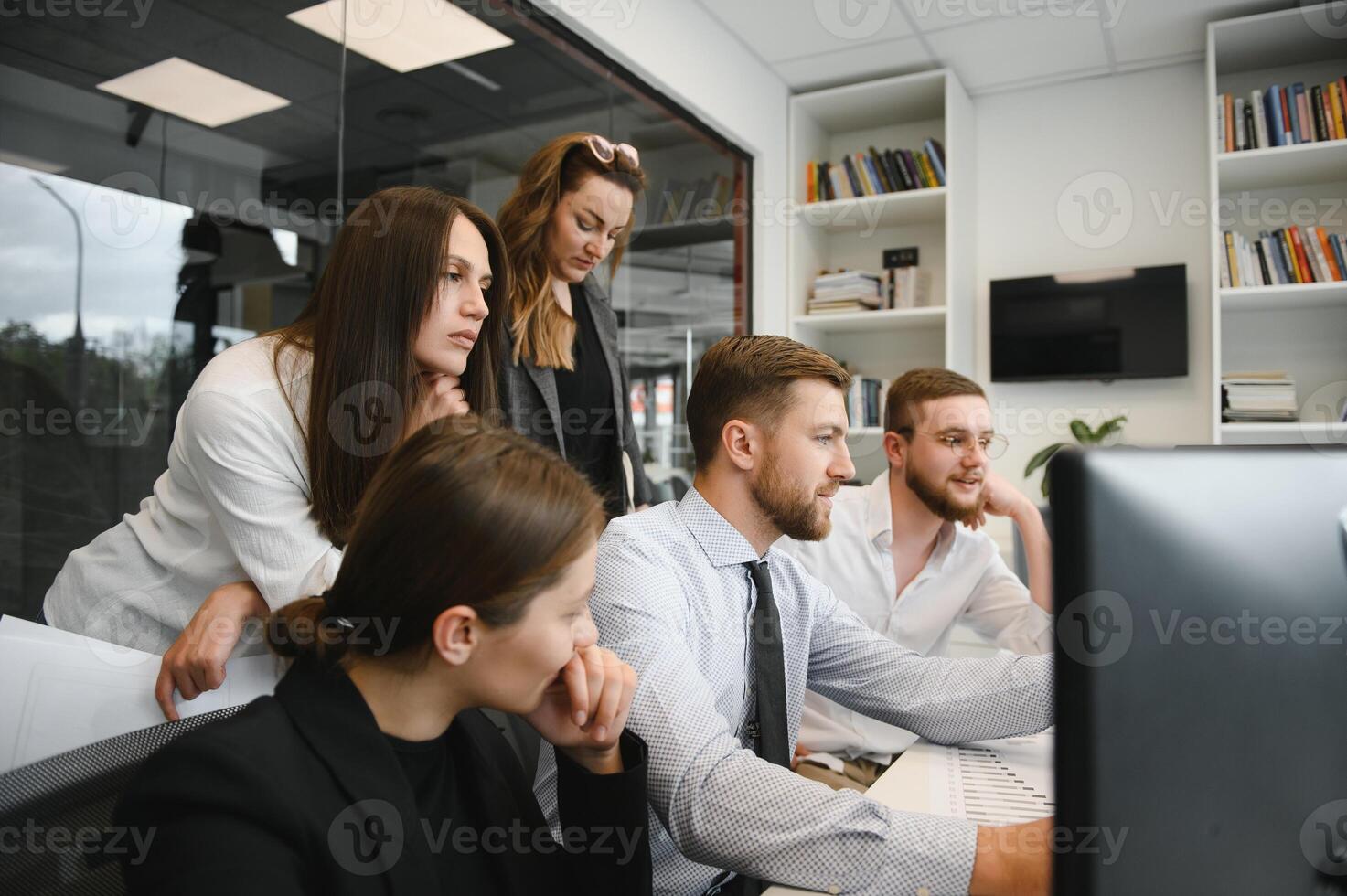 Smiling business people sitting at a desk in front of a laptop computer photo