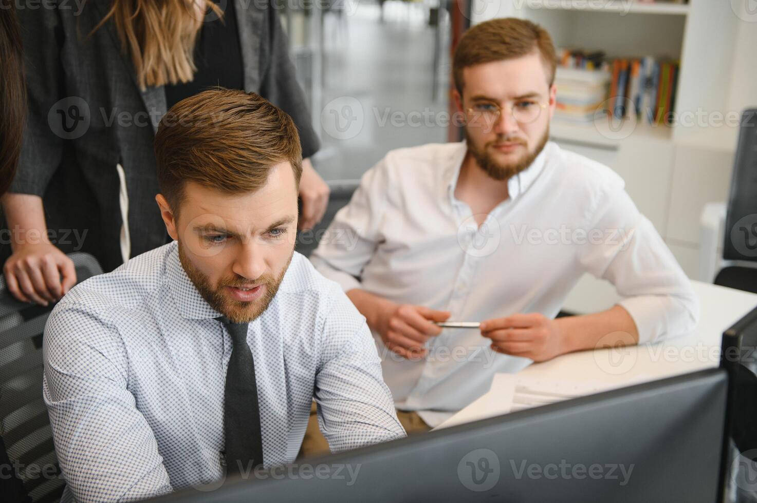 Smiling business people sitting at a desk in front of a laptop computer photo