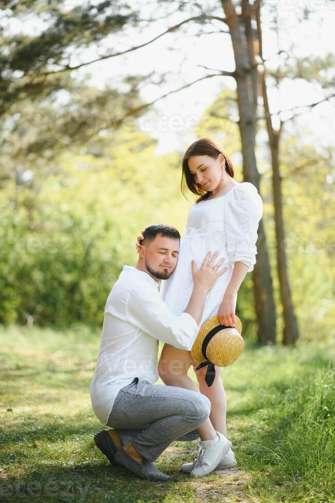 Happy and young pregnant couple hugging in nature photo