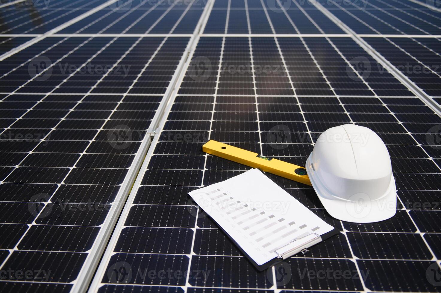Solar cell contractor document with orange engineering team helmet on solar cells panels. Renewable energy and ecology concept. photo
