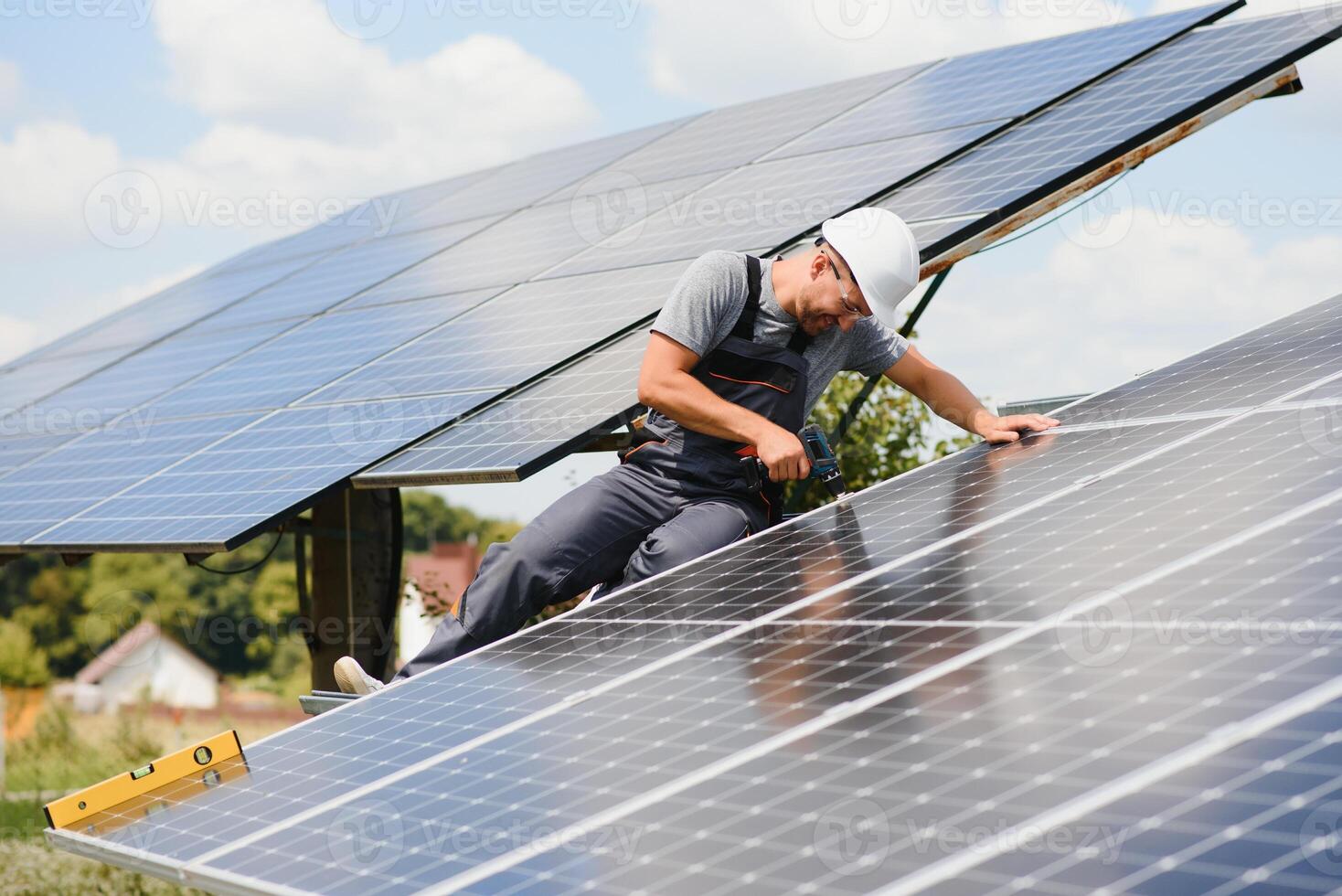 Male engineer in protective helmet installing solar photovoltaic panel system. Alternative energy ecological concept. photo