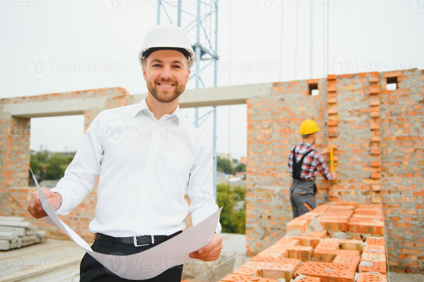 Construction engineer supervising progress of construction project stand on new concrete floor top roof and crane background. photo