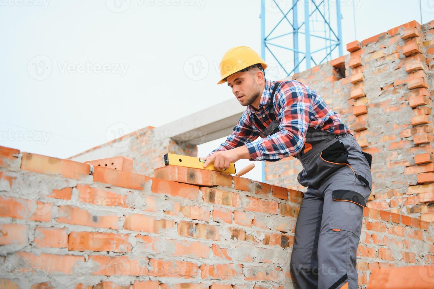 Installing brick wall. Construction worker in uniform and safety equipment have job on building photo