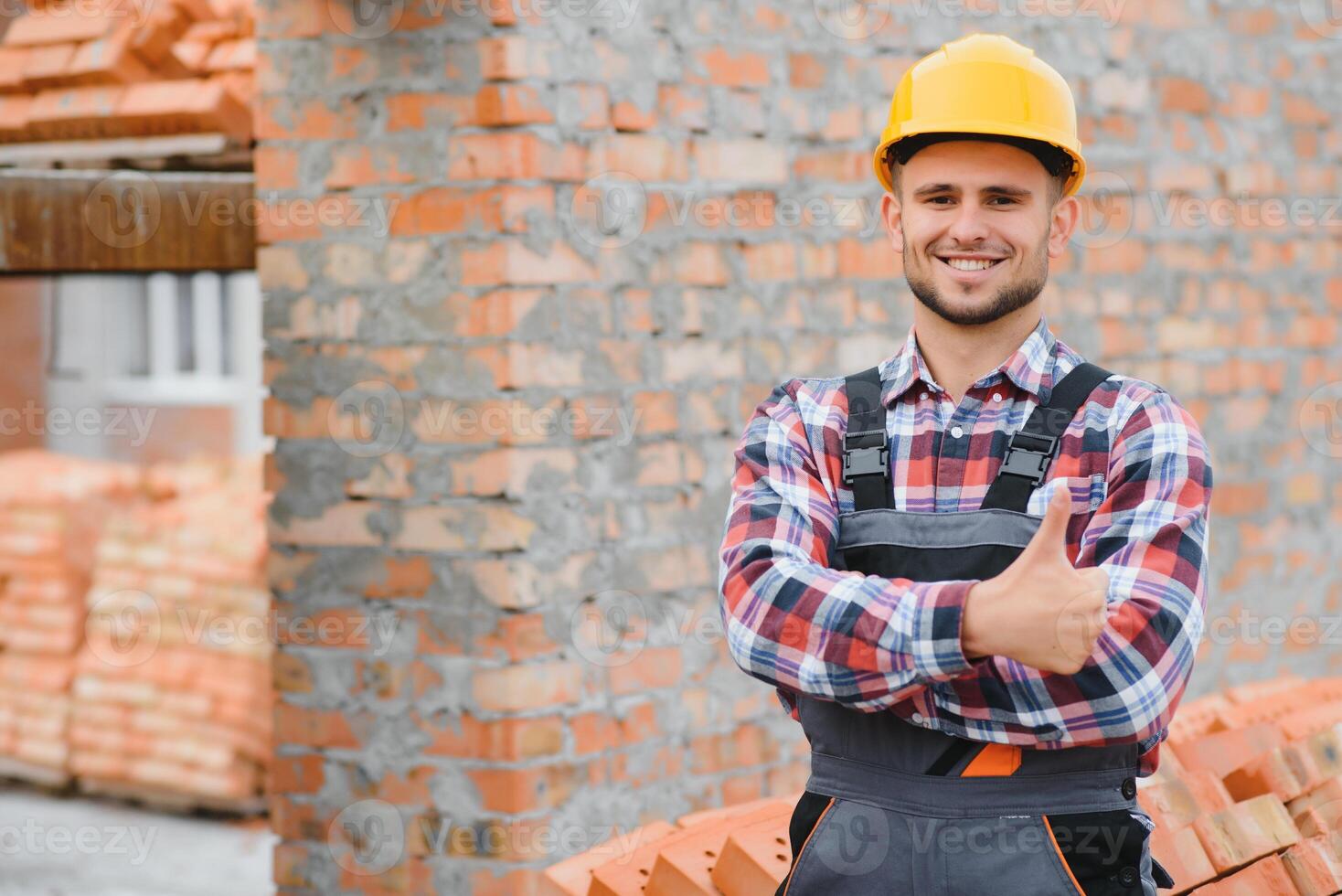Construction worker man in work clothes and a construction helmet. Portrait of positive male builder in hardhat working at construction site. photo