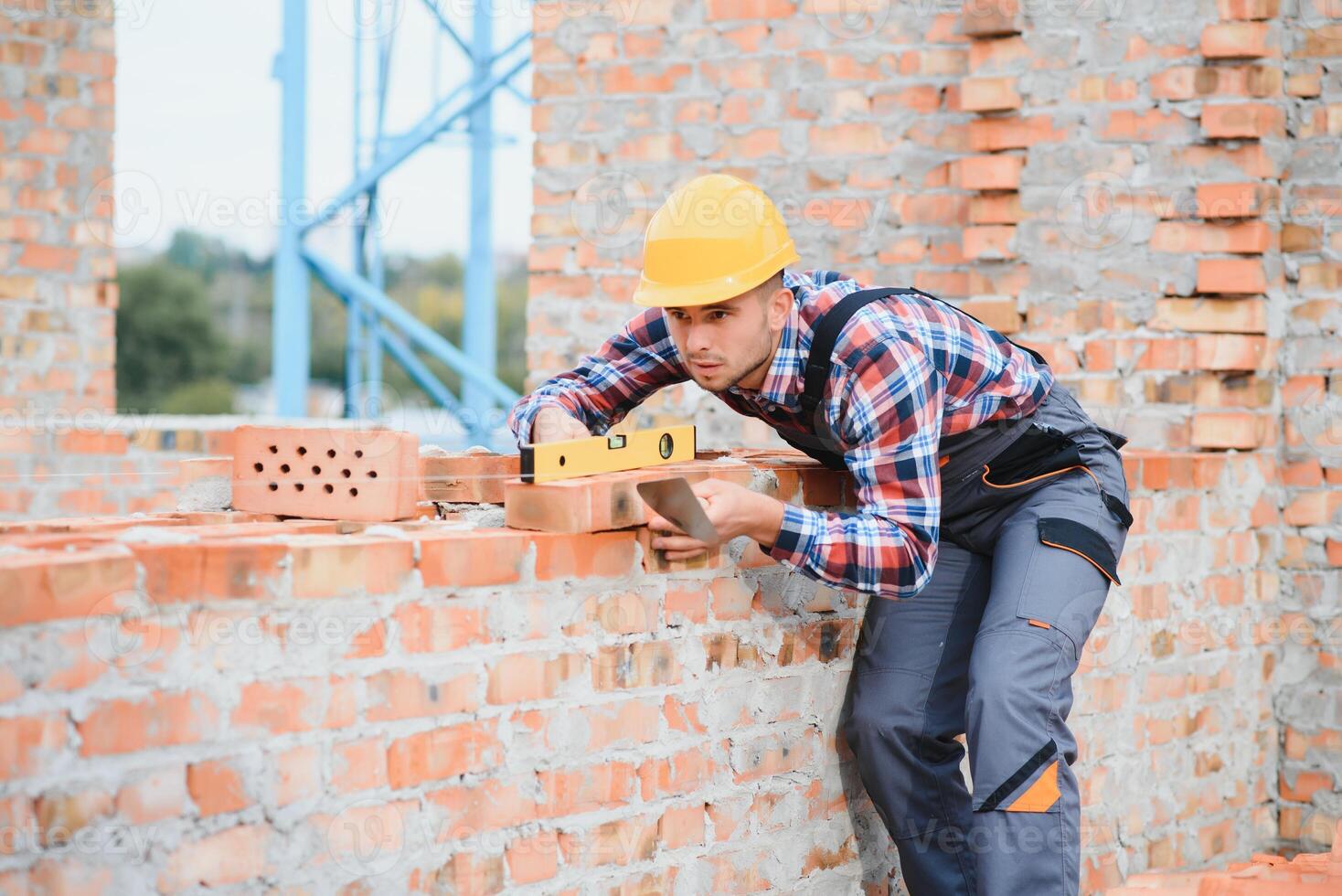 Construction worker man in work clothes and a construction helmet. Portrait of positive male builder in hardhat working at construction site. photo