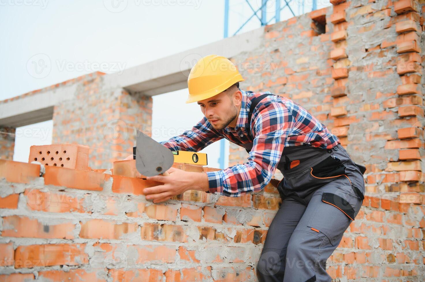 Yellow colored hard hat. Young man working in uniform at construction at daytime. photo