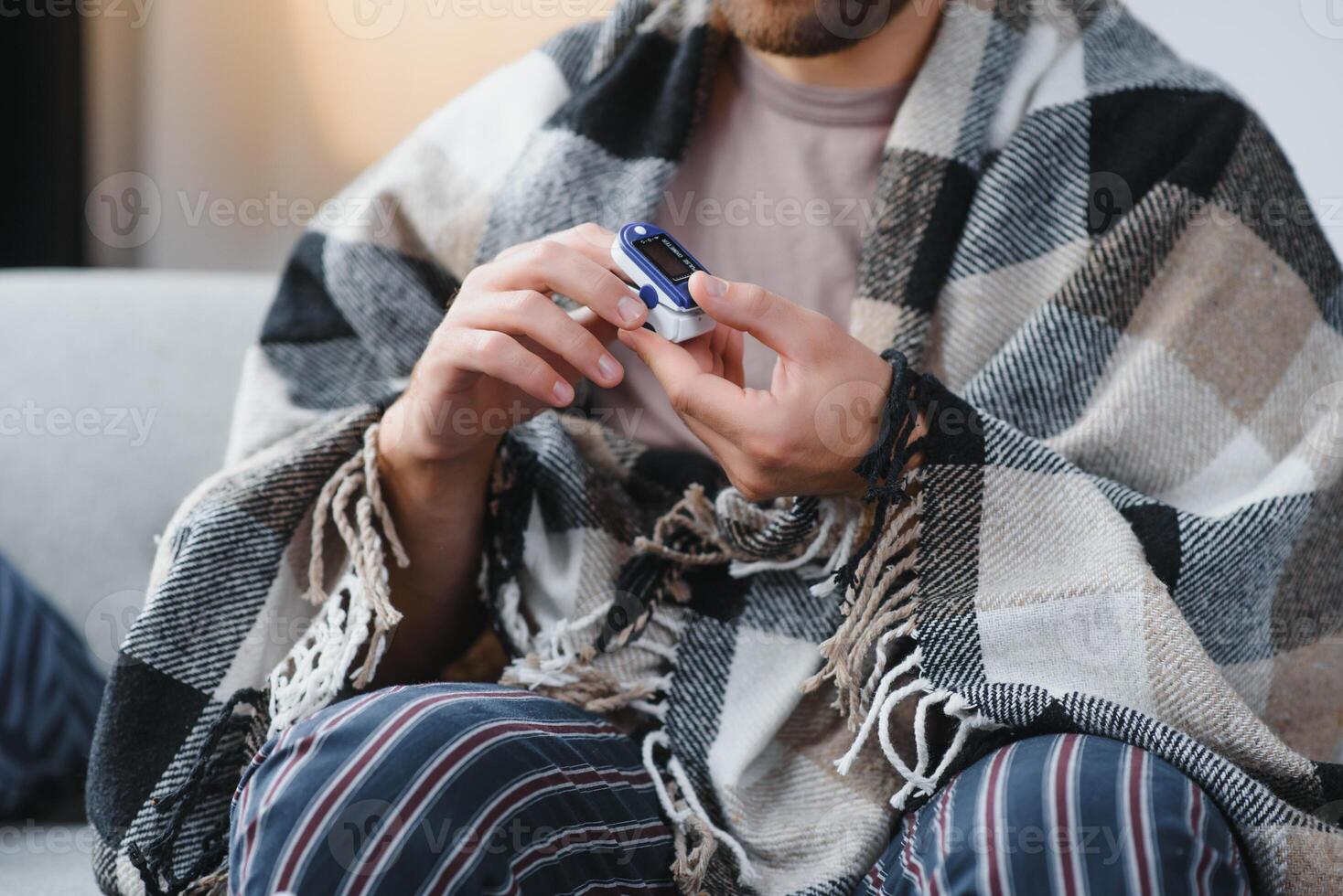 Close up of oximeter on hand of ill person resting while measuring oxygen saturation and pulse pressure to check virus symptoms. Sick adult using device for healthcare treatment. photo