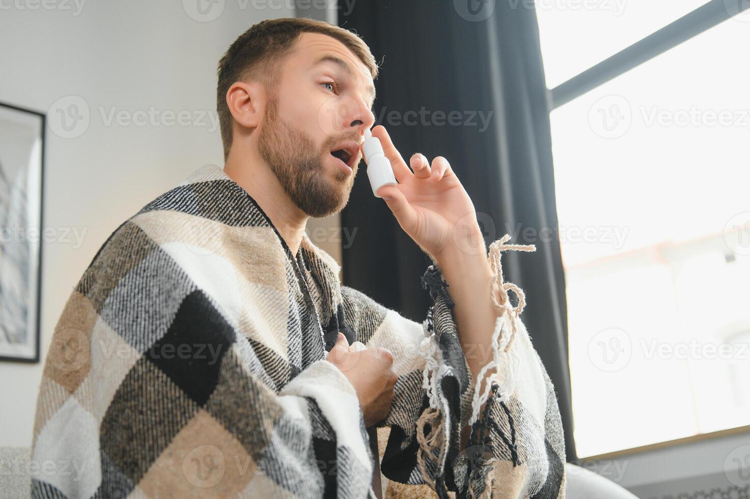 Sick man with nasal spray and paper tissue at home photo