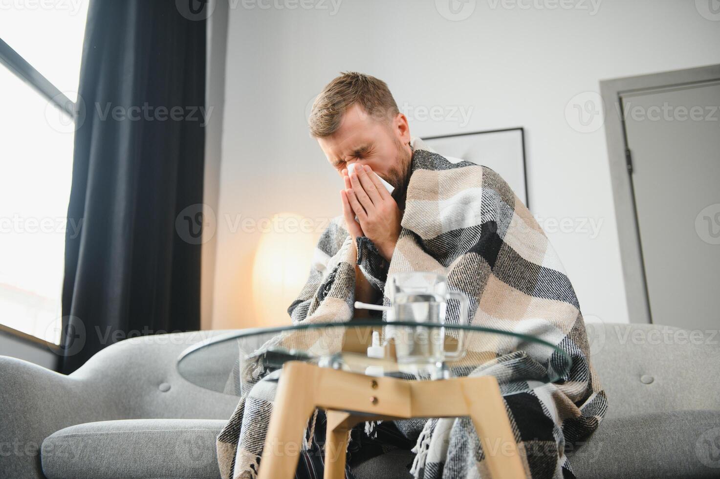 Sick man on sofa at home and blowing nose photo