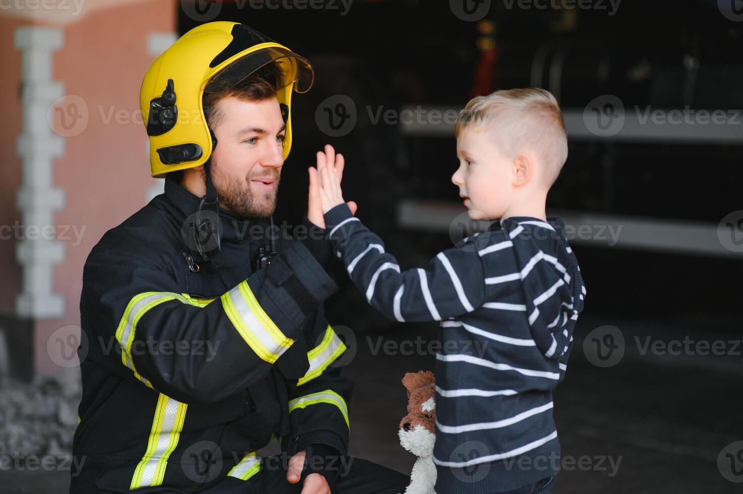 Portrait of rescued little boy with firefighter man standing near fire truck. Firefighter in fire fighting operation. photo