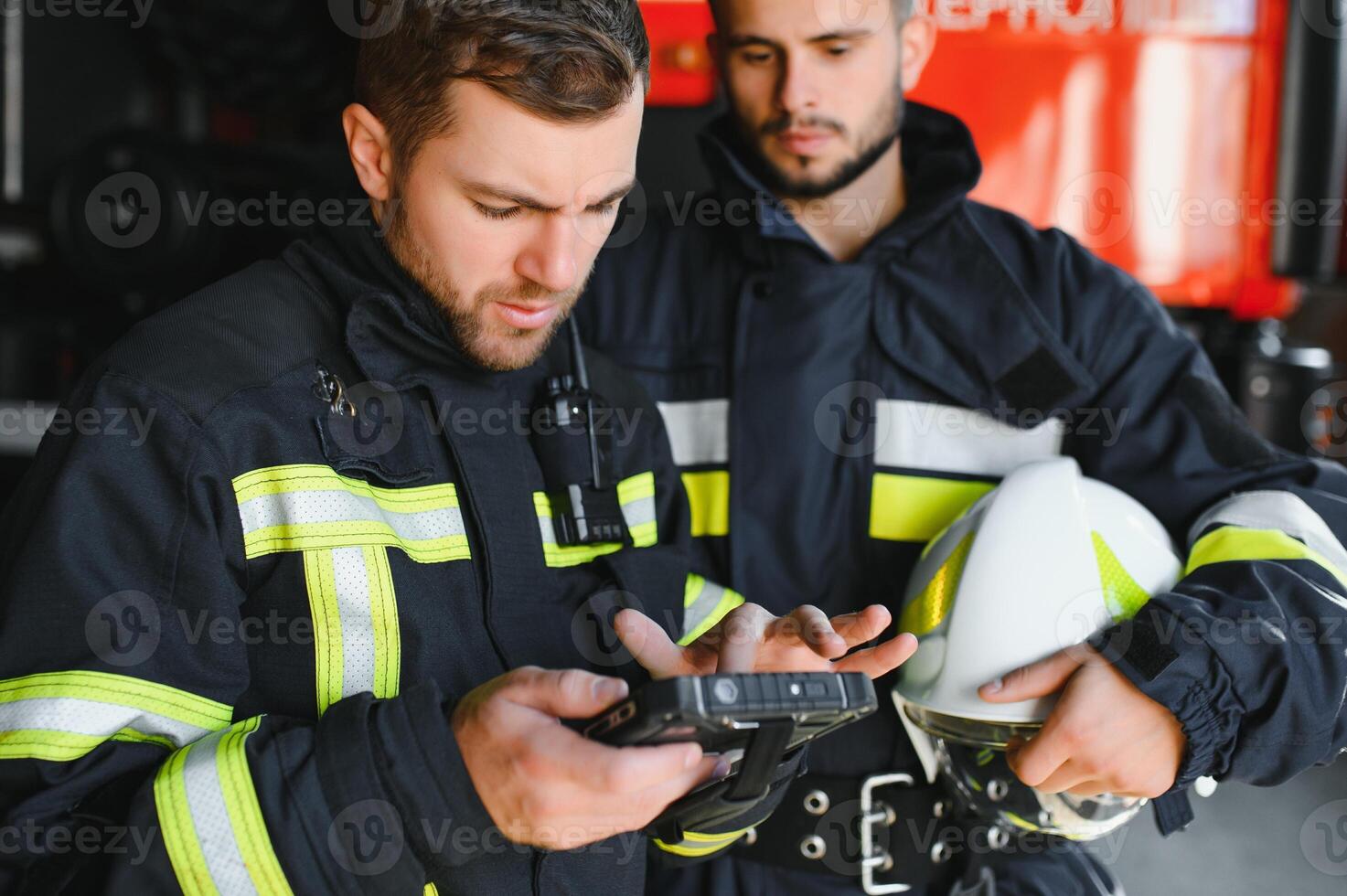Portrait of two firefighters in fire fighting operation, fireman in protective clothing and helmet using tablet computer in action fighting photo