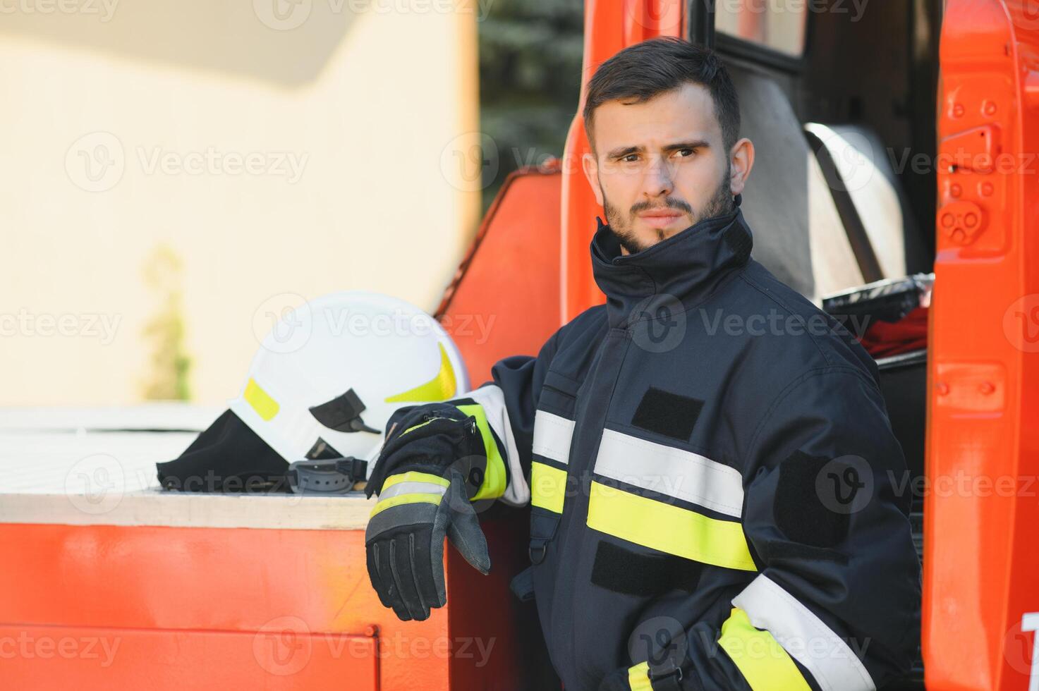 Firefighter portrait on duty. Photo fireman with gas mask and helmet near fire engine.