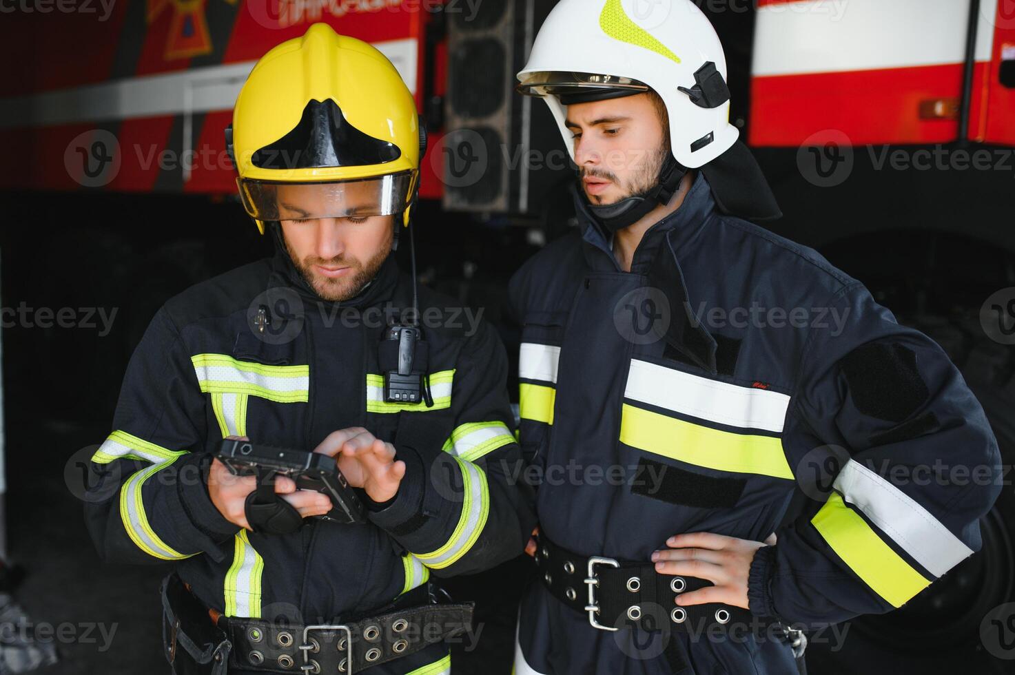 Portrait of two firefighters in fire fighting operation, fireman in protective clothing and helmet using tablet computer in action fighting photo
