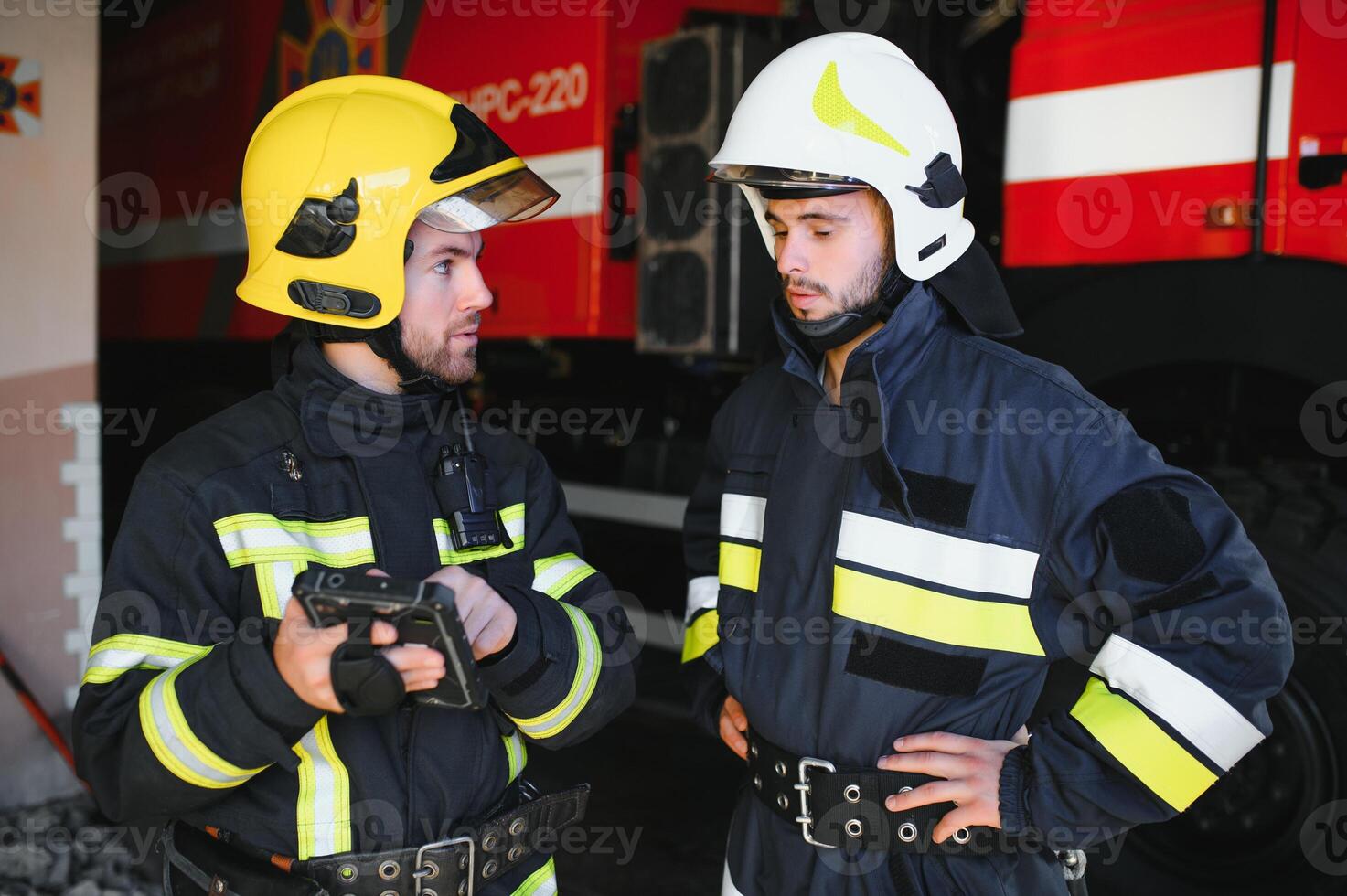 Portrait of two firefighters in fire fighting operation, fireman in protective clothing and helmet using tablet computer in action fighting photo