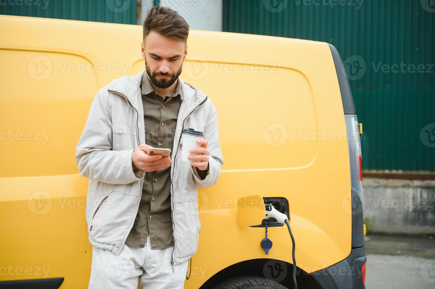 Man charging electric car by the work photo