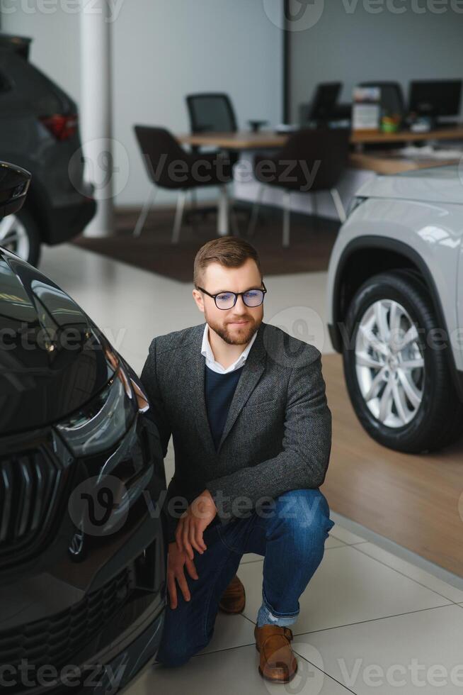 Man adult customer male buyer client wears classic suit white shirt chooses auto wants to buy new automobile touch check car in showroom vehicle salon dealership store motor show indoor. Sales concept photo