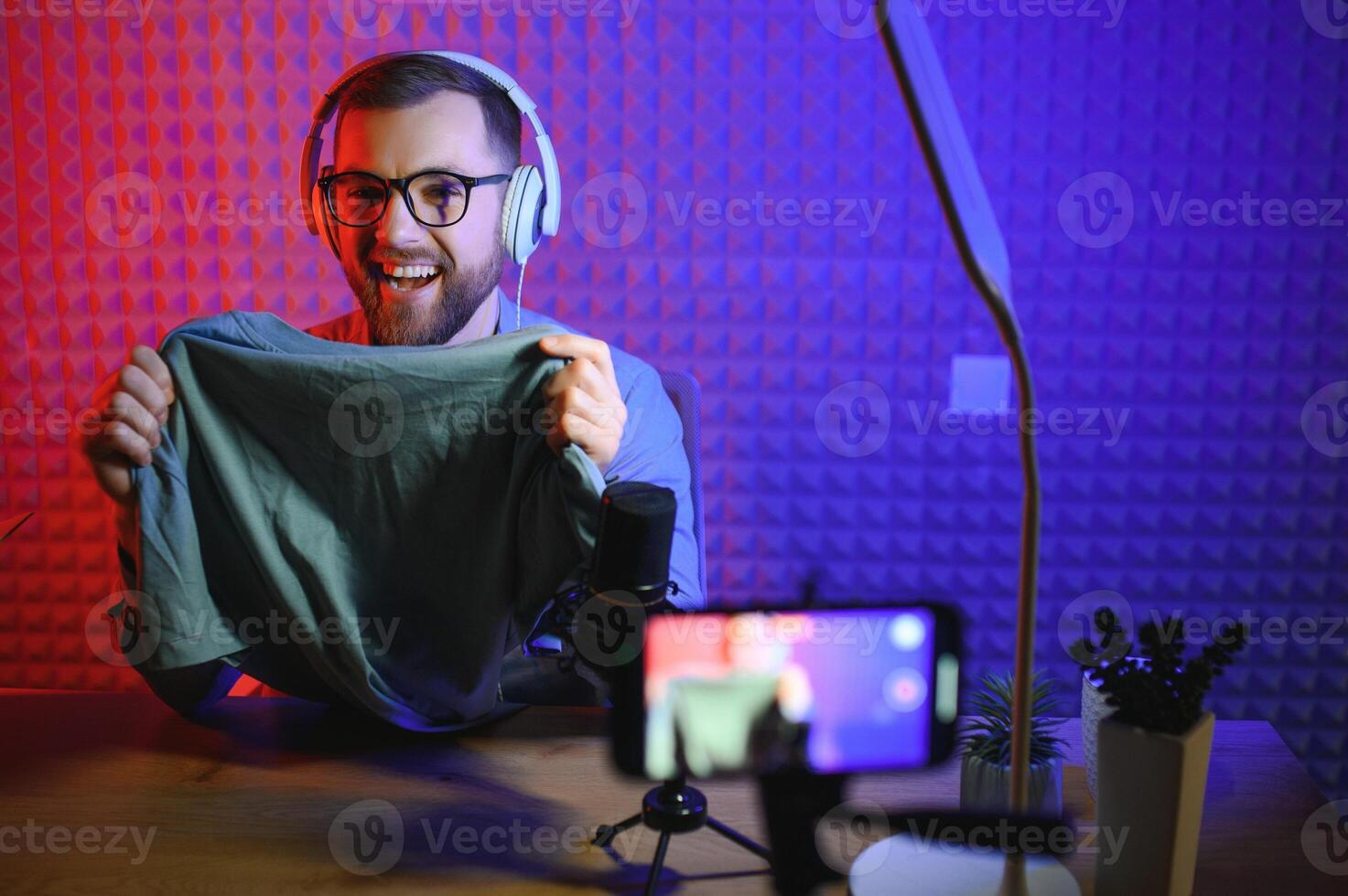 vlogger using smartphone to film podcast in studio. blogger with mobile phone, microphone and headphones filming for social media broadcasting career. photo