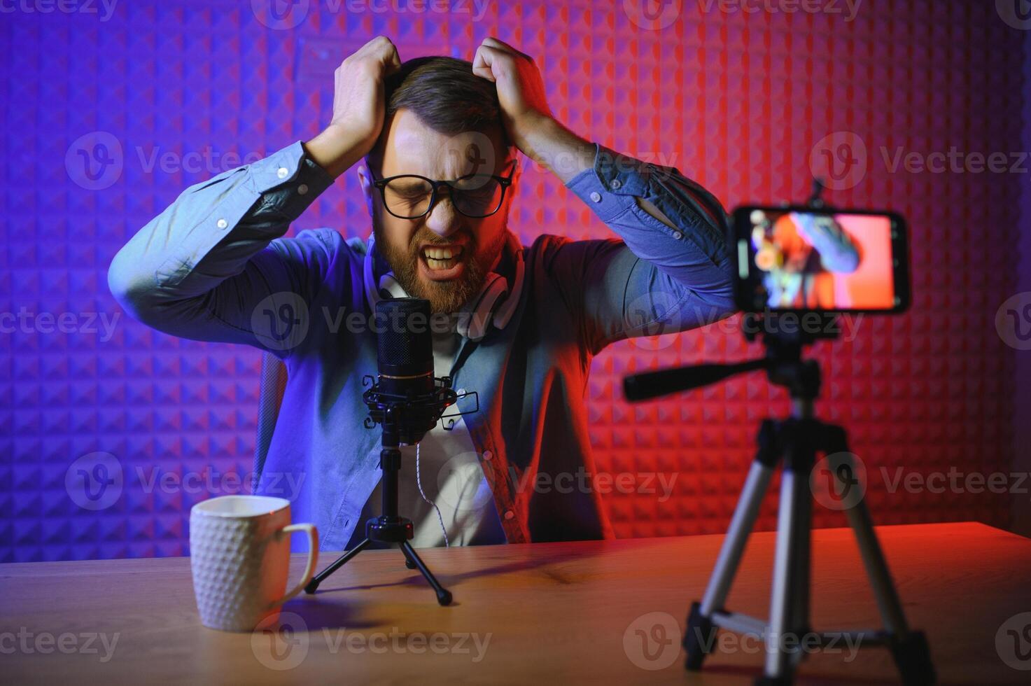 Young man recording or streaming podcast using microphone at his small broadcast studio. Content creator. photo