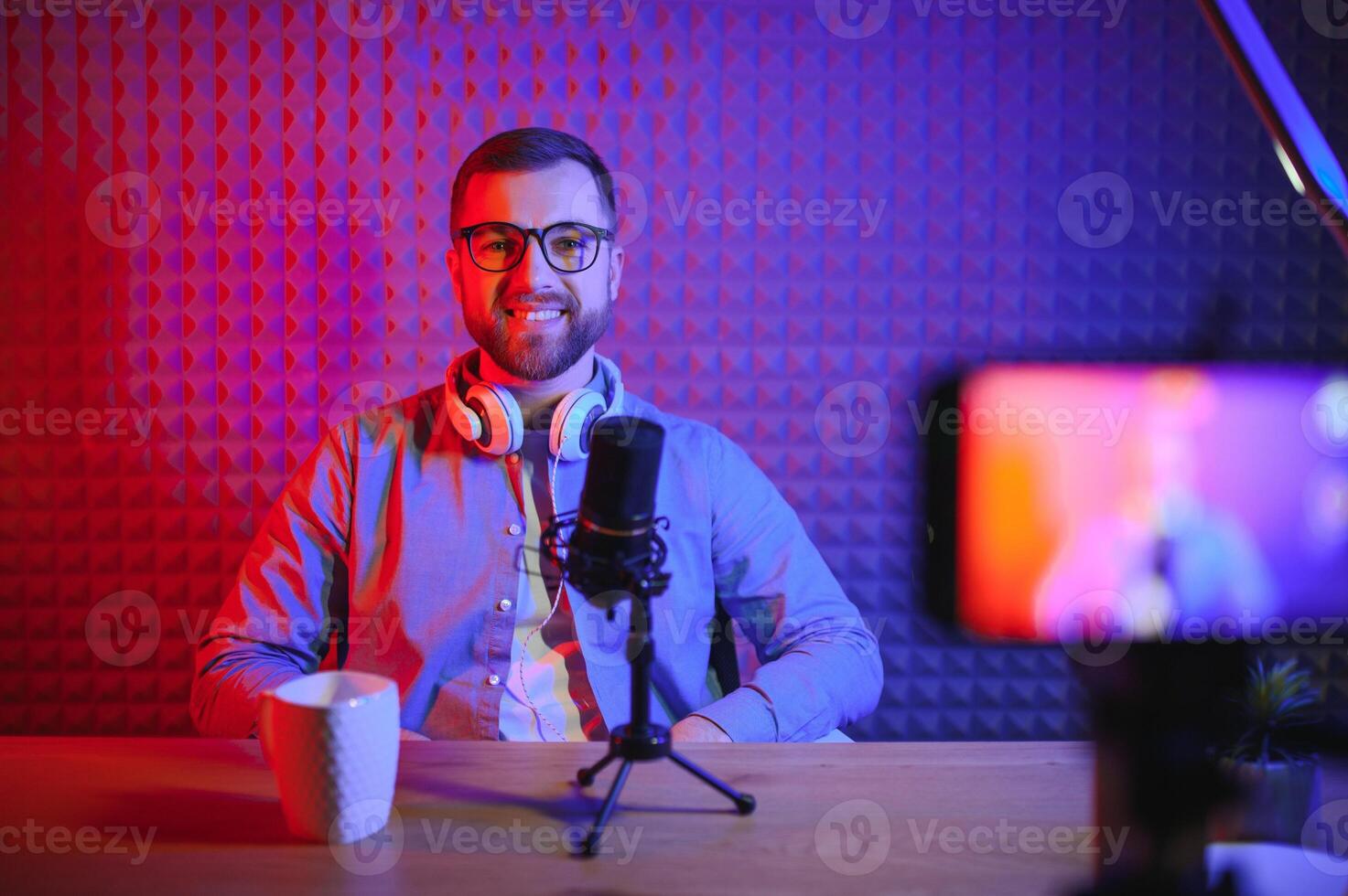 Young man recording or streaming podcast using microphone at his small broadcast studio. Content creator. photo
