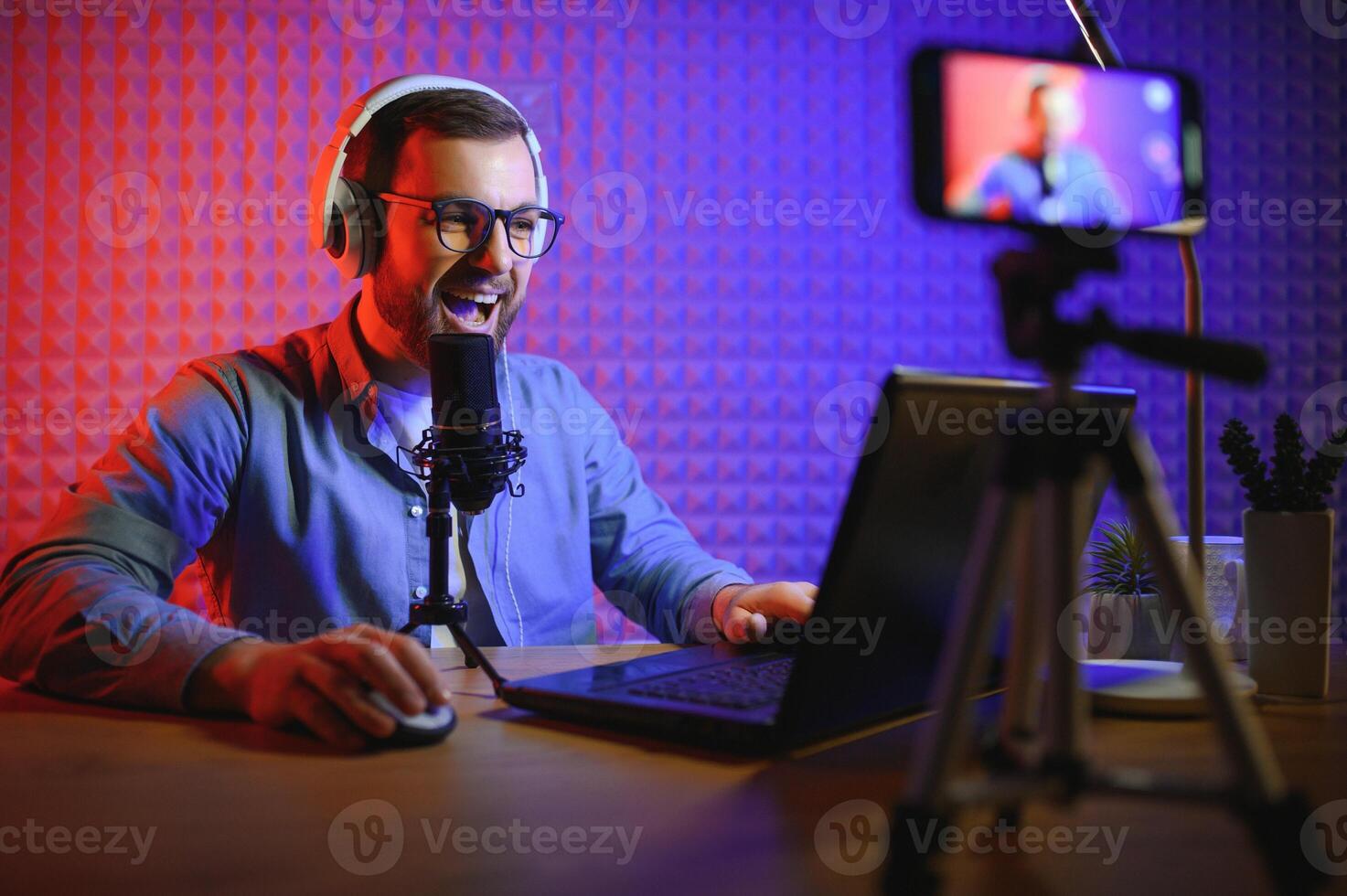 Young man recording or streaming podcast using microphone at his small broadcast studio. Content creator. photo