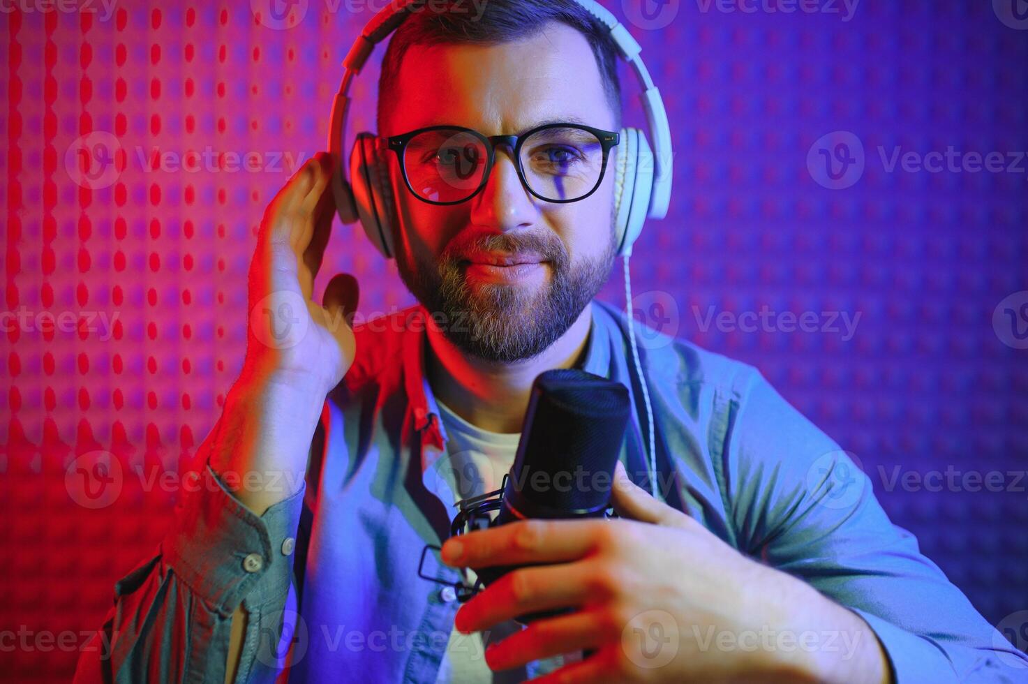 Young man recording or streaming podcast using microphone at his small broadcast studio. Content creator. photo