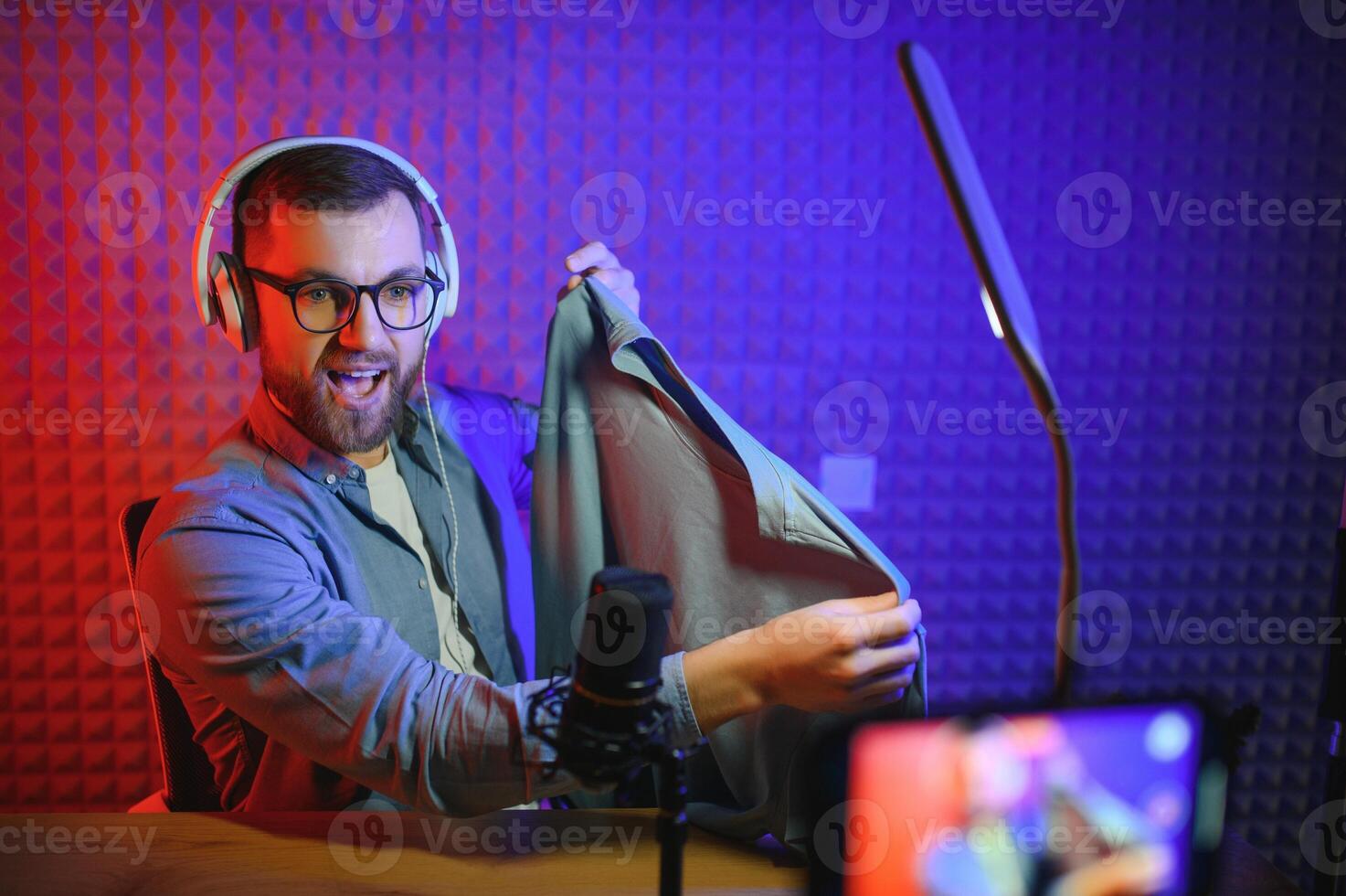 Young man recording or streaming podcast using microphone at his small broadcast studio. Content creator. photo