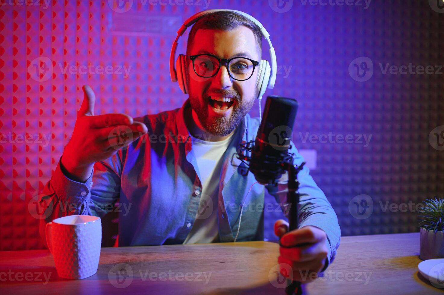 Young man recording or streaming podcast using microphone at his small broadcast studio. Content creator. photo