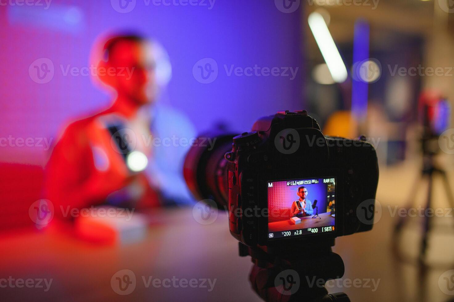 Male technology blogger recording blog or vlog review of new smartphone, showing it on camera at home studio. Blogging, Work from Home concept. Selective focus. Web Banner photo