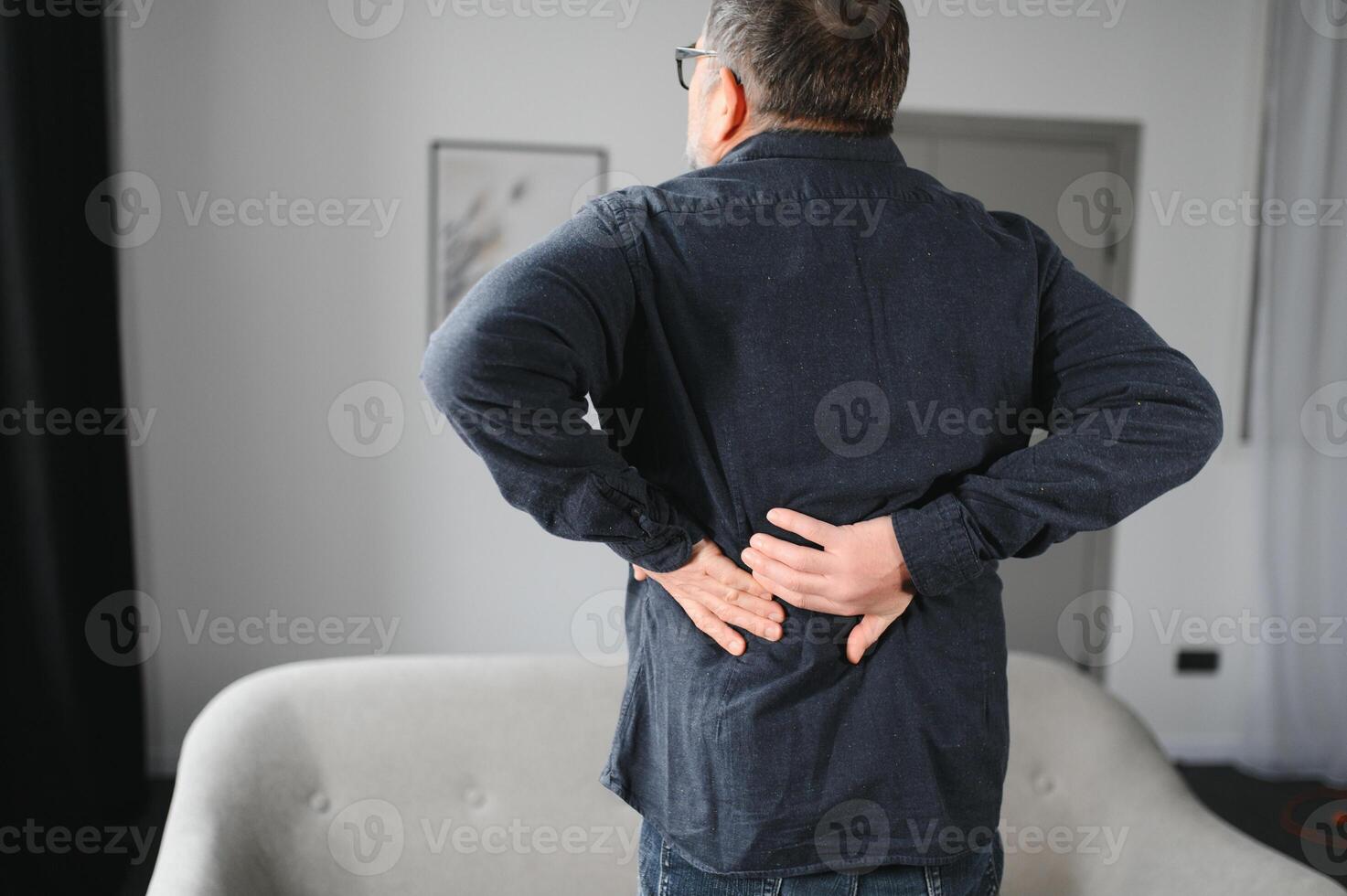 Senior man is suffering from pain in lower back at home photo